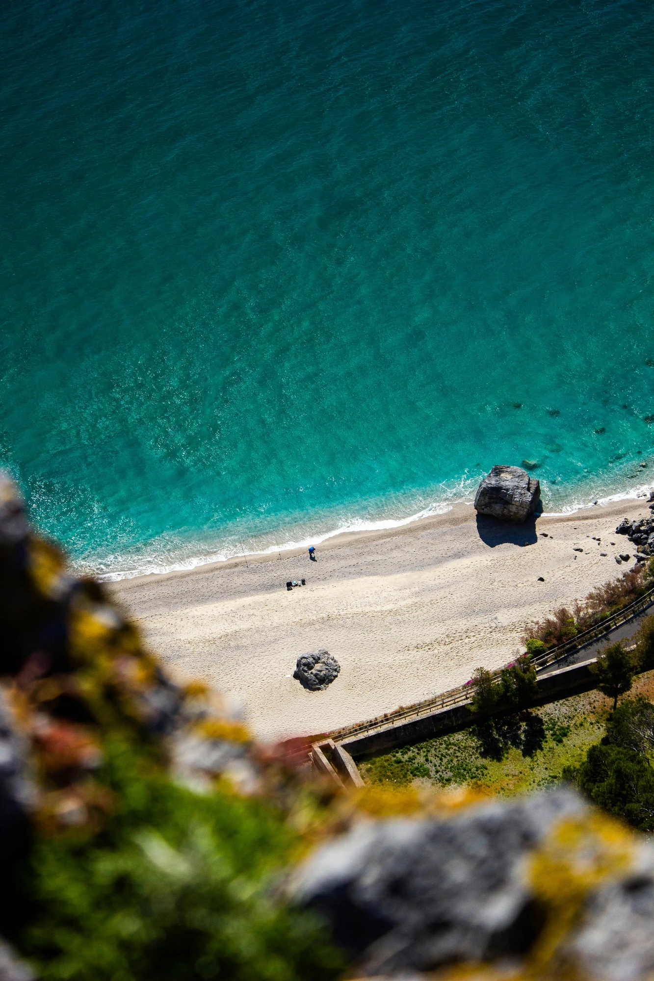 Blick von oben auf türkisblaues Wasser mit hellem Sandstrand