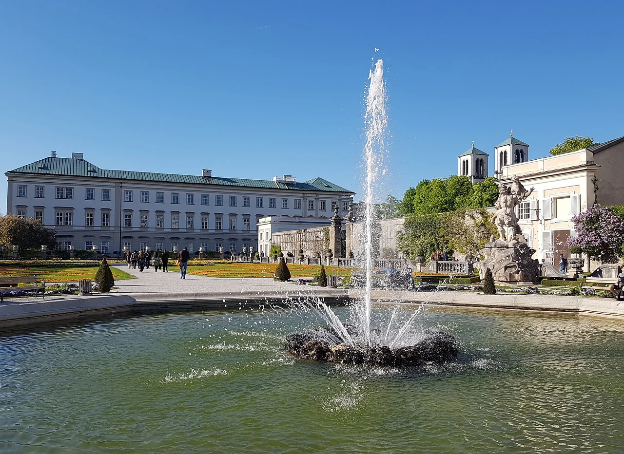 Springbrunnen im Mirabellgarten mit Schloss Mirabell im Hintergrund, Salzburg, Österreich.