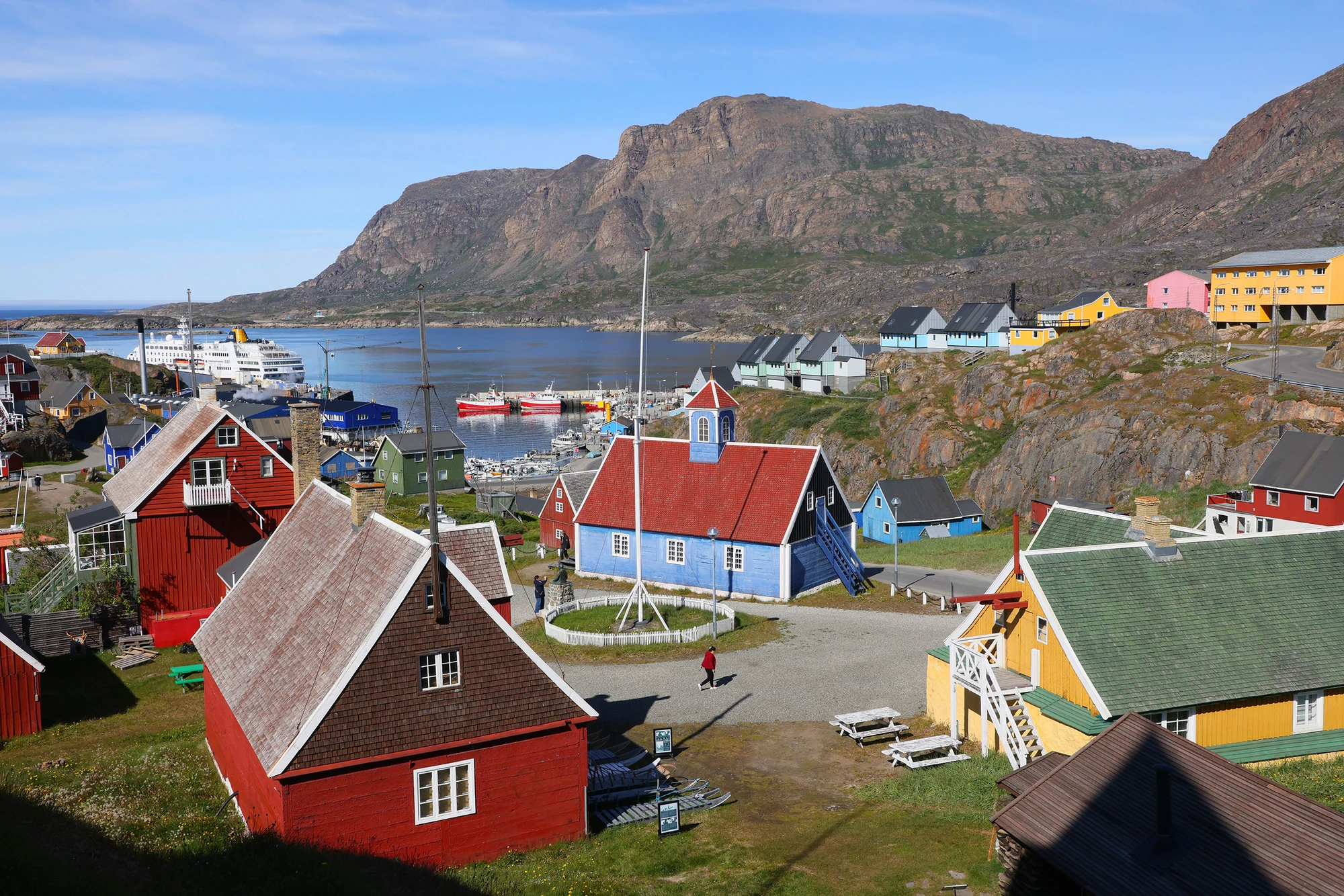 Bunte Häuser in einem grünenländischen Dorf mit Blick auf das Wasser.