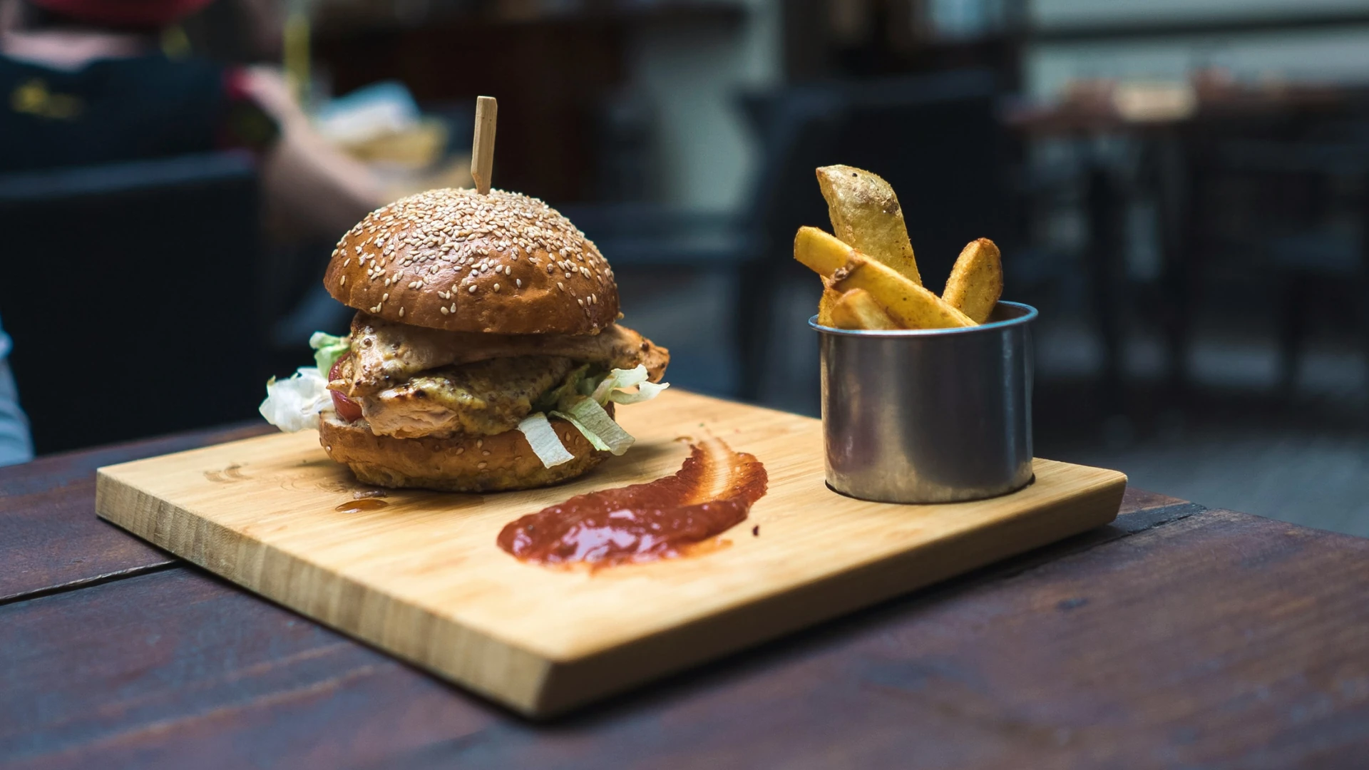 Städtereise Budapest zeigt einen saftigen Burger auf einem Holzbrett, serviert mit knusprigen Pommes und einer Sauce, bereit zum Genießen.