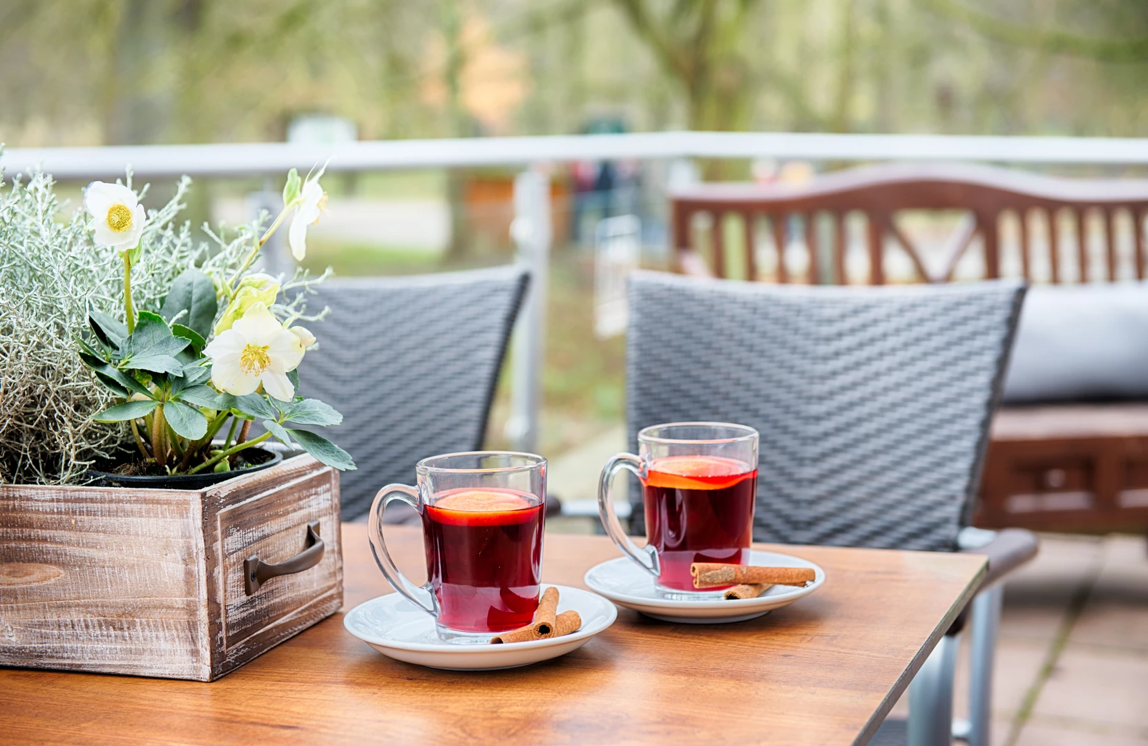 Ein Tisch auf der Außenterrasse mit Blumen und 2 Tassen Tee.