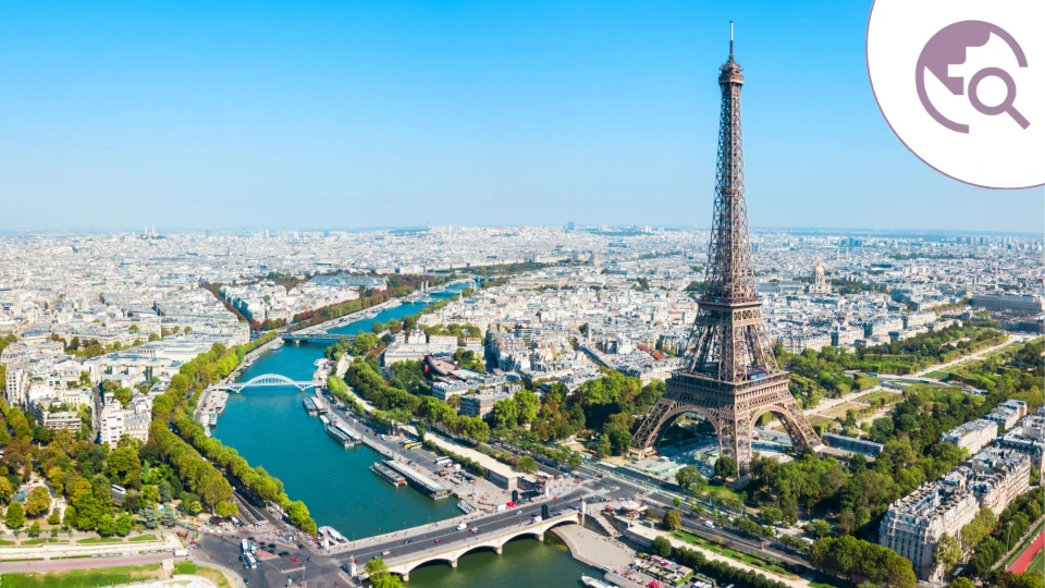 Dieses Foto zeigt eine beeindruckende Luftaufnahme von Paris mit dem Eiffelturm als zentralem Blickfang. Die Seine schlängelt sich durch die Stadt, umgeben von historischen Gebäuden und grünen Parkanlagen, die das typische Pariser Stadtbild prägen.