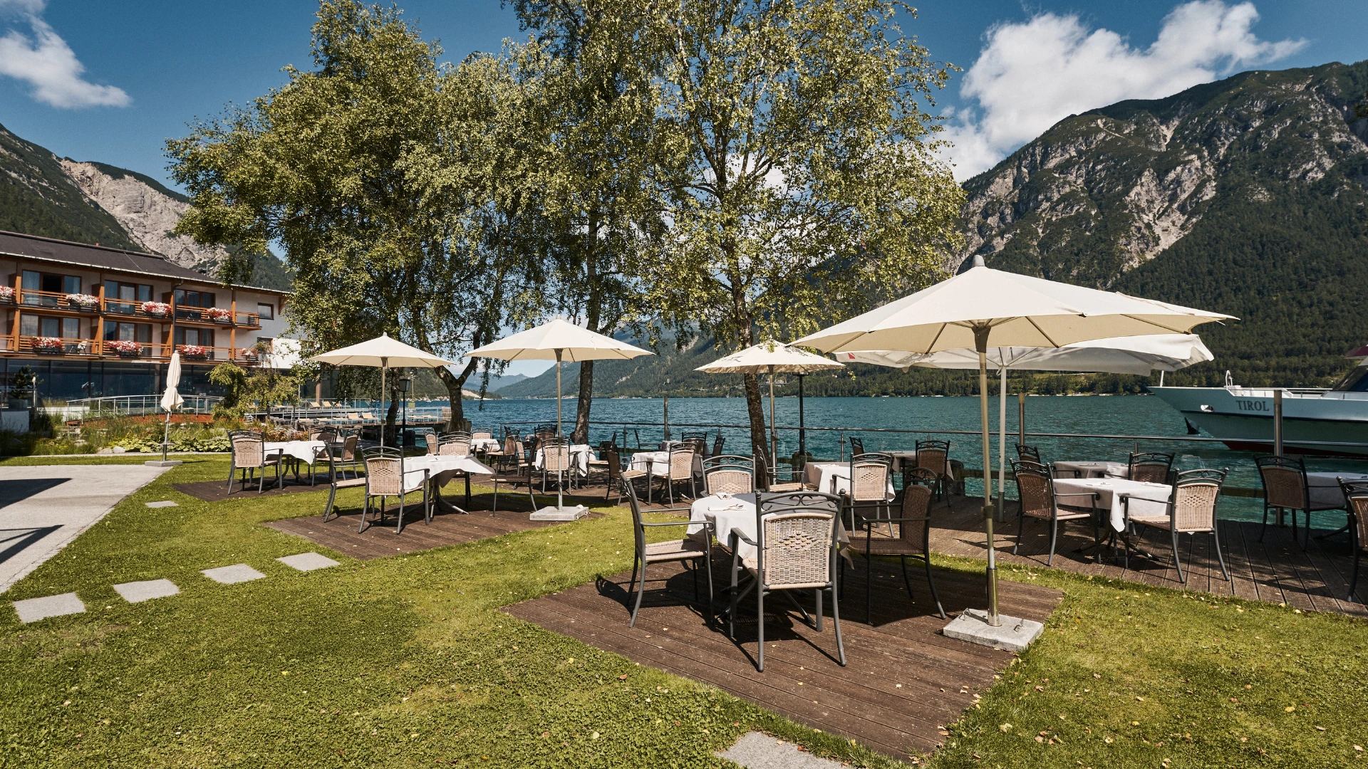 Die idyllische Terrasse des aja Fürstenhaus am Achensee lädt zum Verweilen ein. Mit Blick auf den glitzernden Achensee und umgeben von imposanten Bergkulissen bietet dieser Außenbereich ein unvergleichliches Ambiente für entspannte Mahlzeiten im Freien.