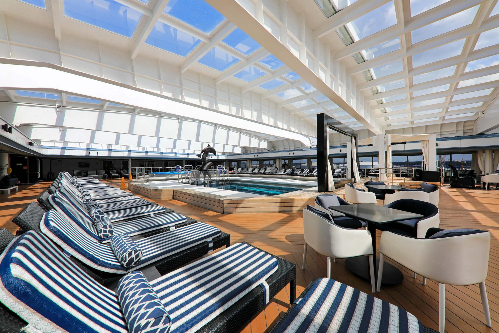 Stilvoller Poolbereich auf einem Kreuzfahrtschiff mit Liegen und Sonnendach.