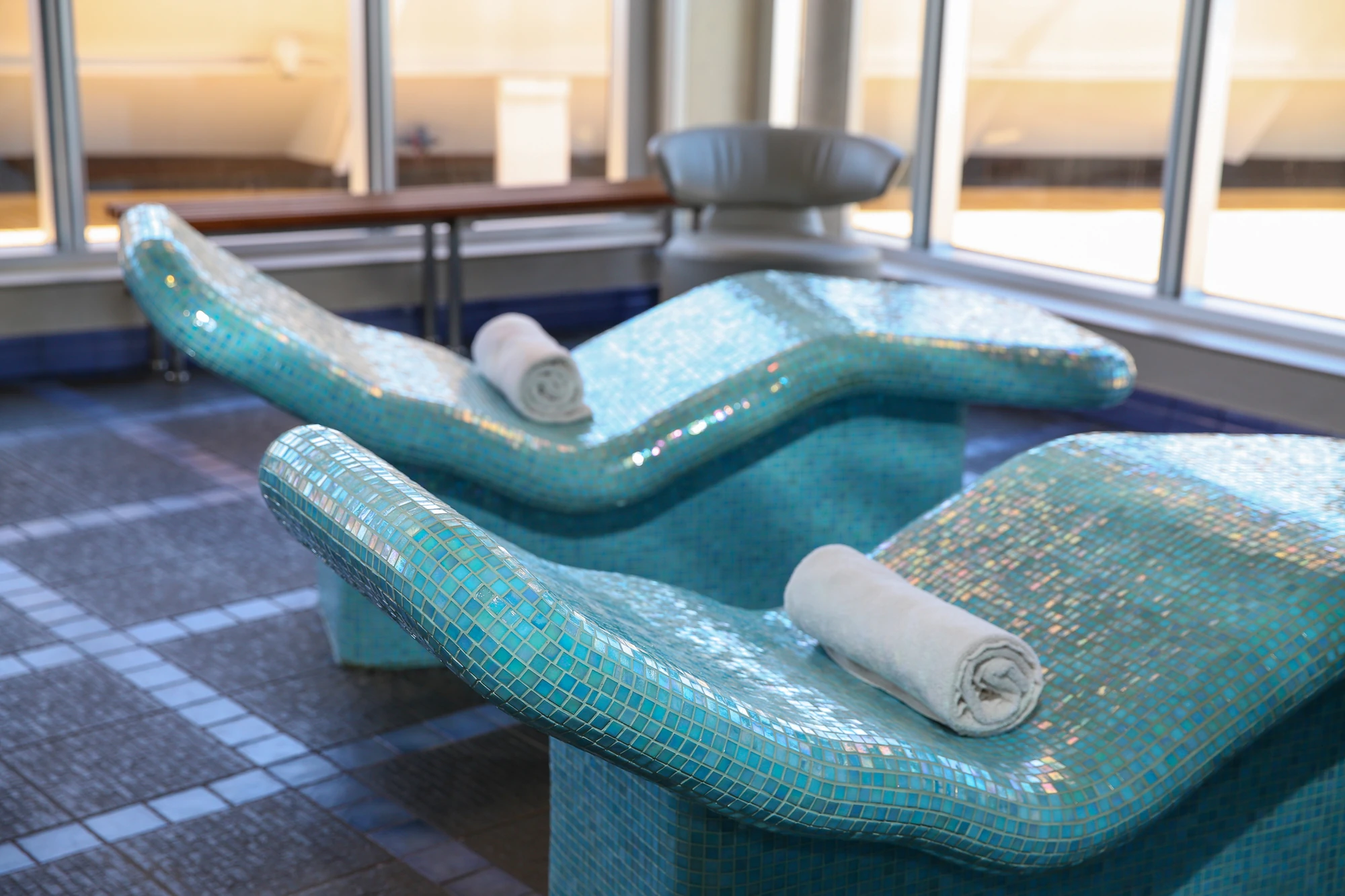 Heller Entspannungsbereich mit großen Fenstern und stilvollen Liegen.