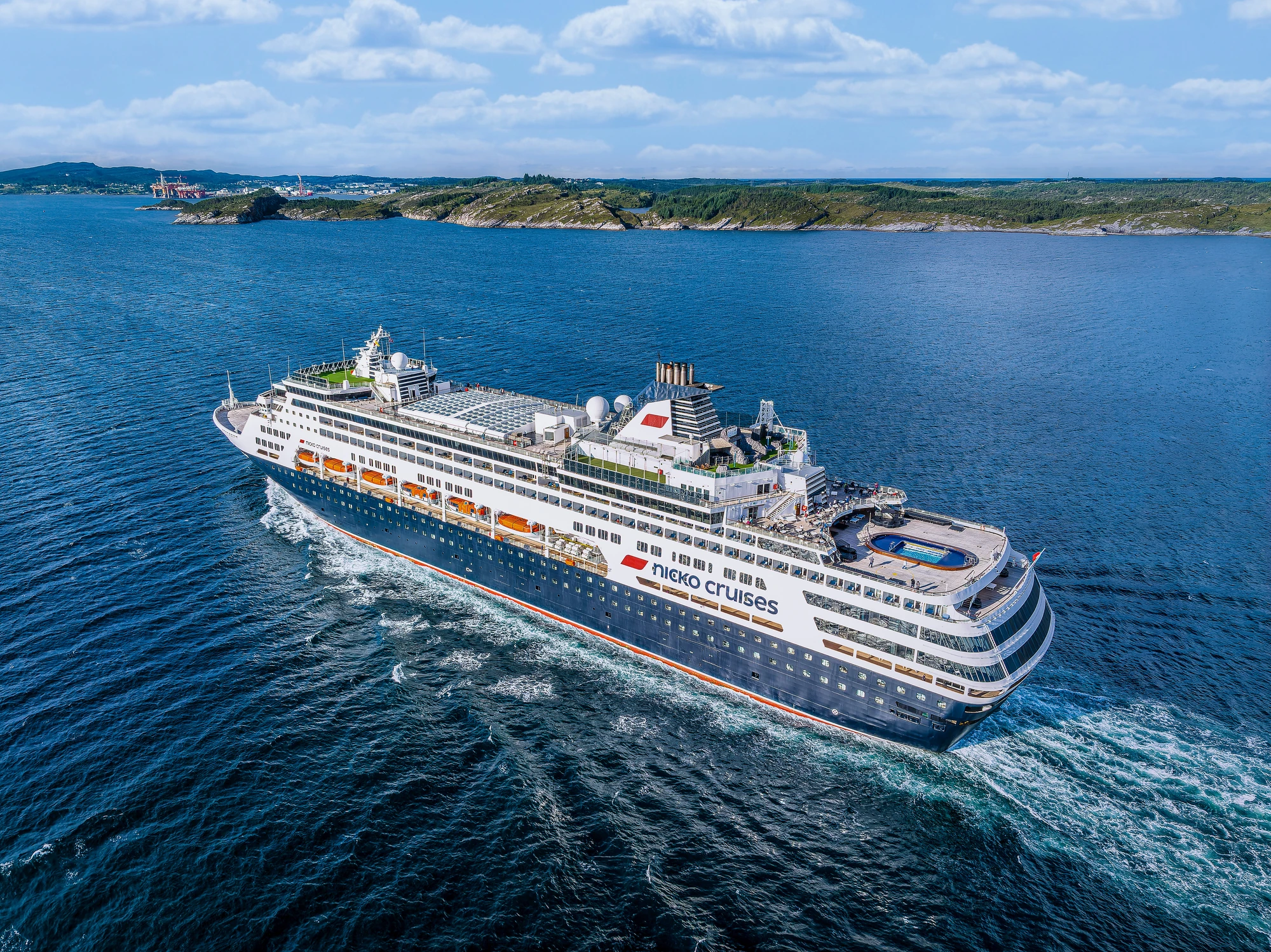 Kreuzfahrtschiff von 'Hurtigruten' mit mehreren Decks und Pool, fährt durch ruhiges Wasser in der Nähe von Bergen, Norwegen.