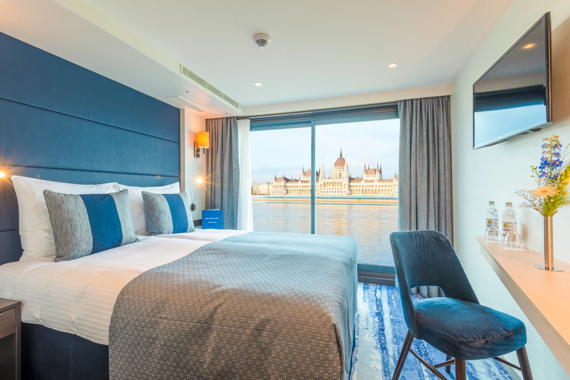 2-Bettkabine mit blauen Kissen in einem modernen Kabinenzimmer, Blick auf das ungarische Parlamentsgebäude durch große Fenster.