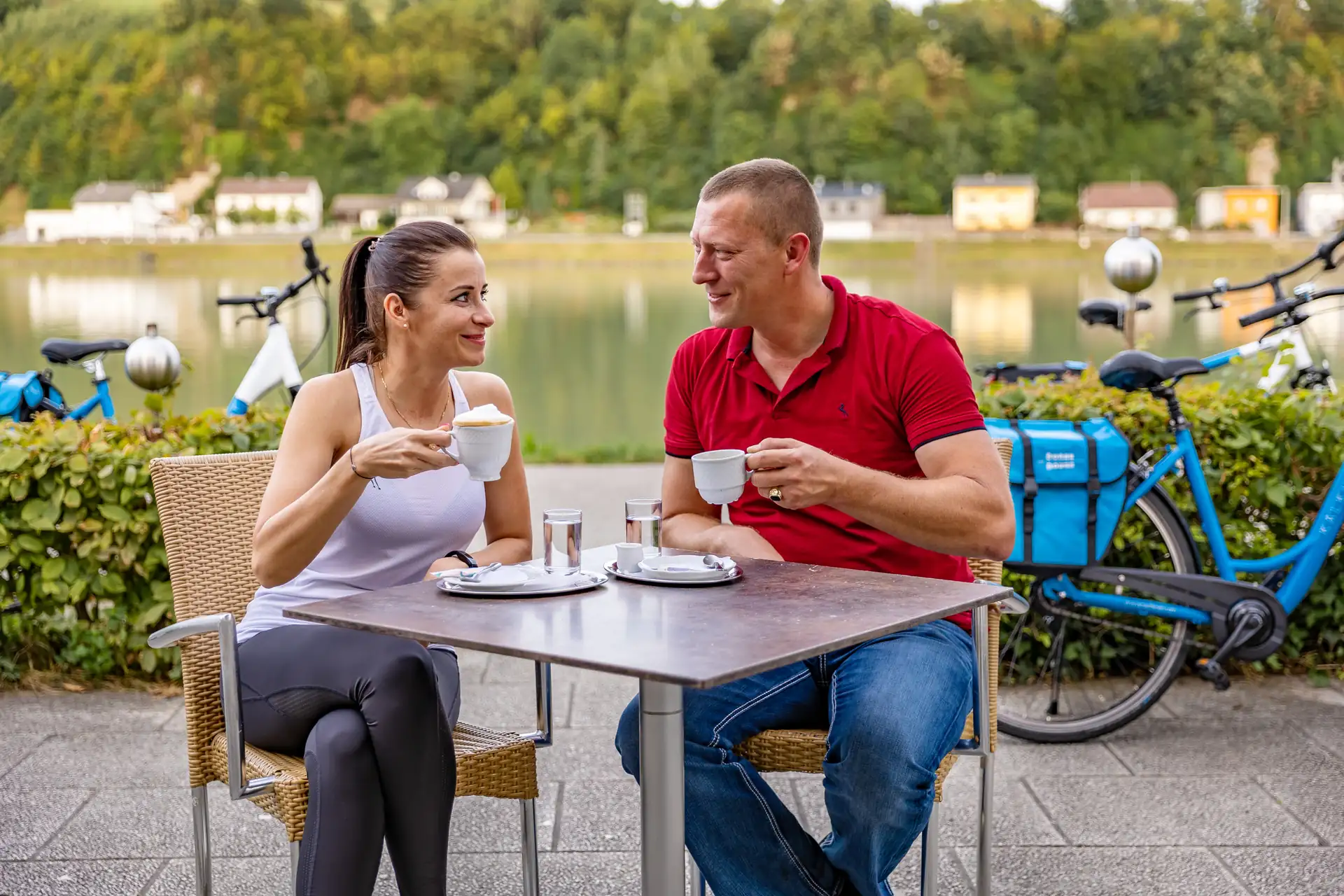 Pärchen bei einer Kaffeepause auf einer Terrasse in Aschach an der Donau mit Leihrädern im Hintergrund.