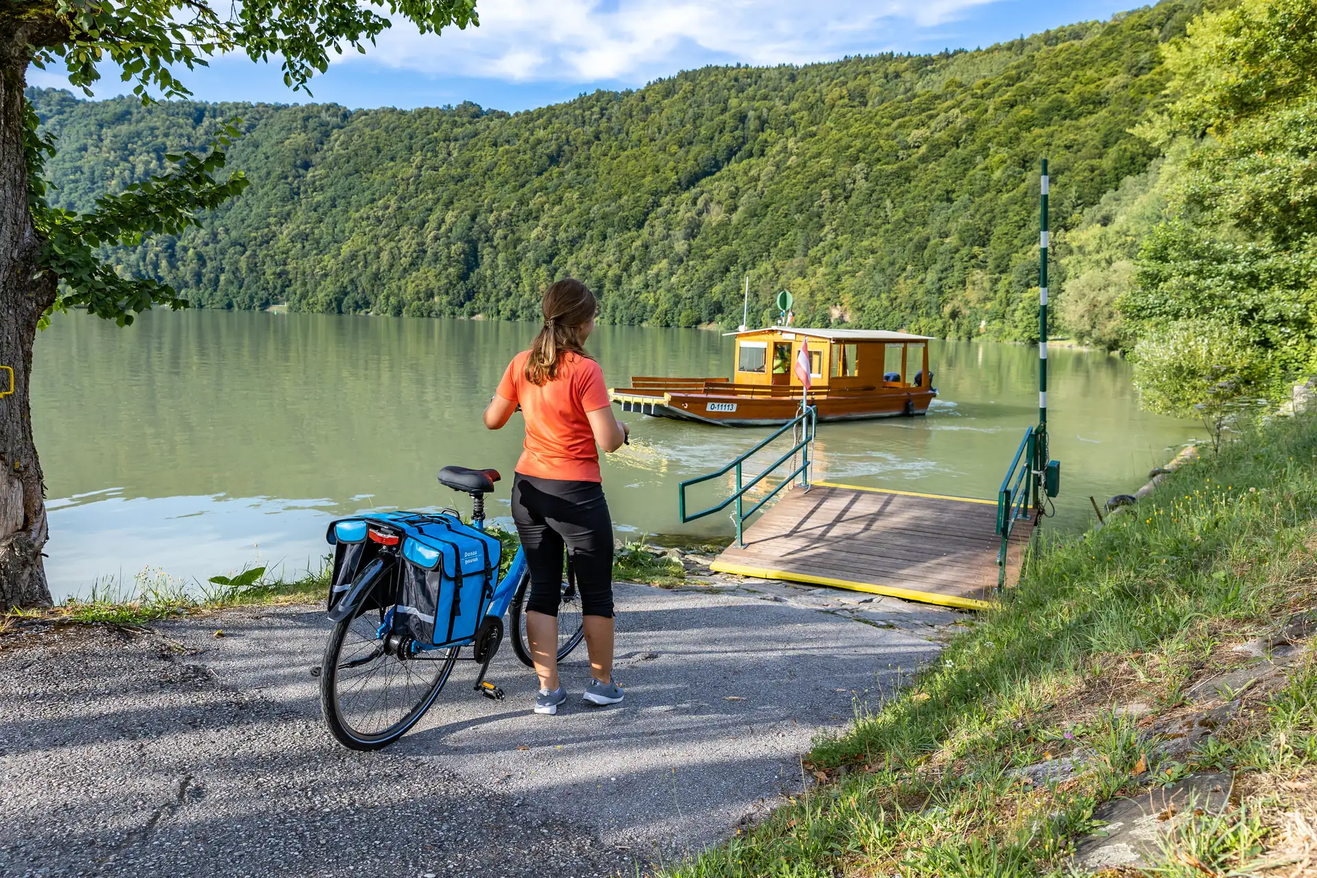 Radfahrerin schiebt Rad zum Fähranleger in Schlögen.