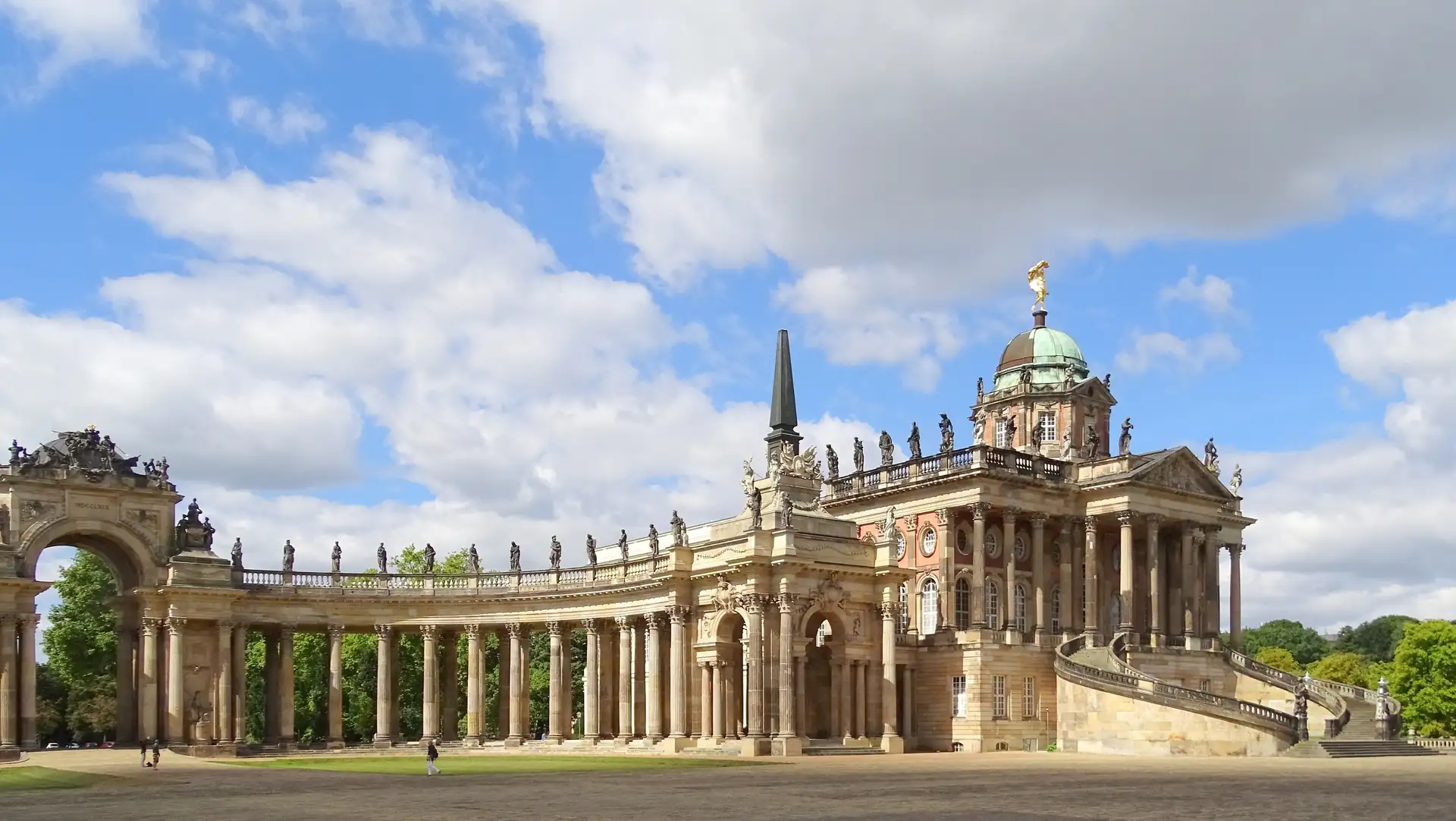 Historisches Gebäude der Universität Potsdam mit Säulengang, Kuppel und zahlreichen Statuen unter bewölktem Himmel
