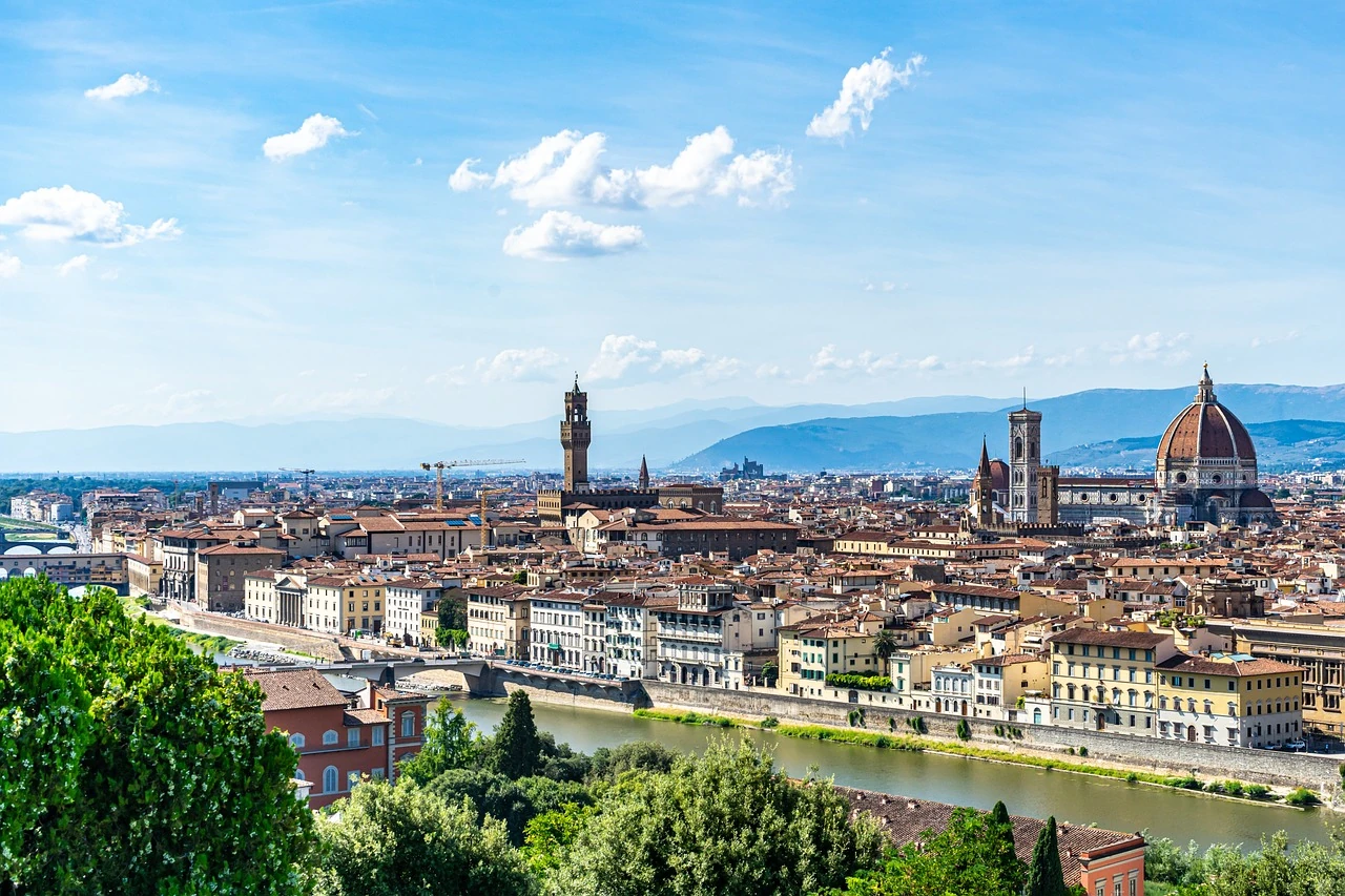 Blick auf die typischen Häuser in Florenz am Fluss vor einer Bergkulisse