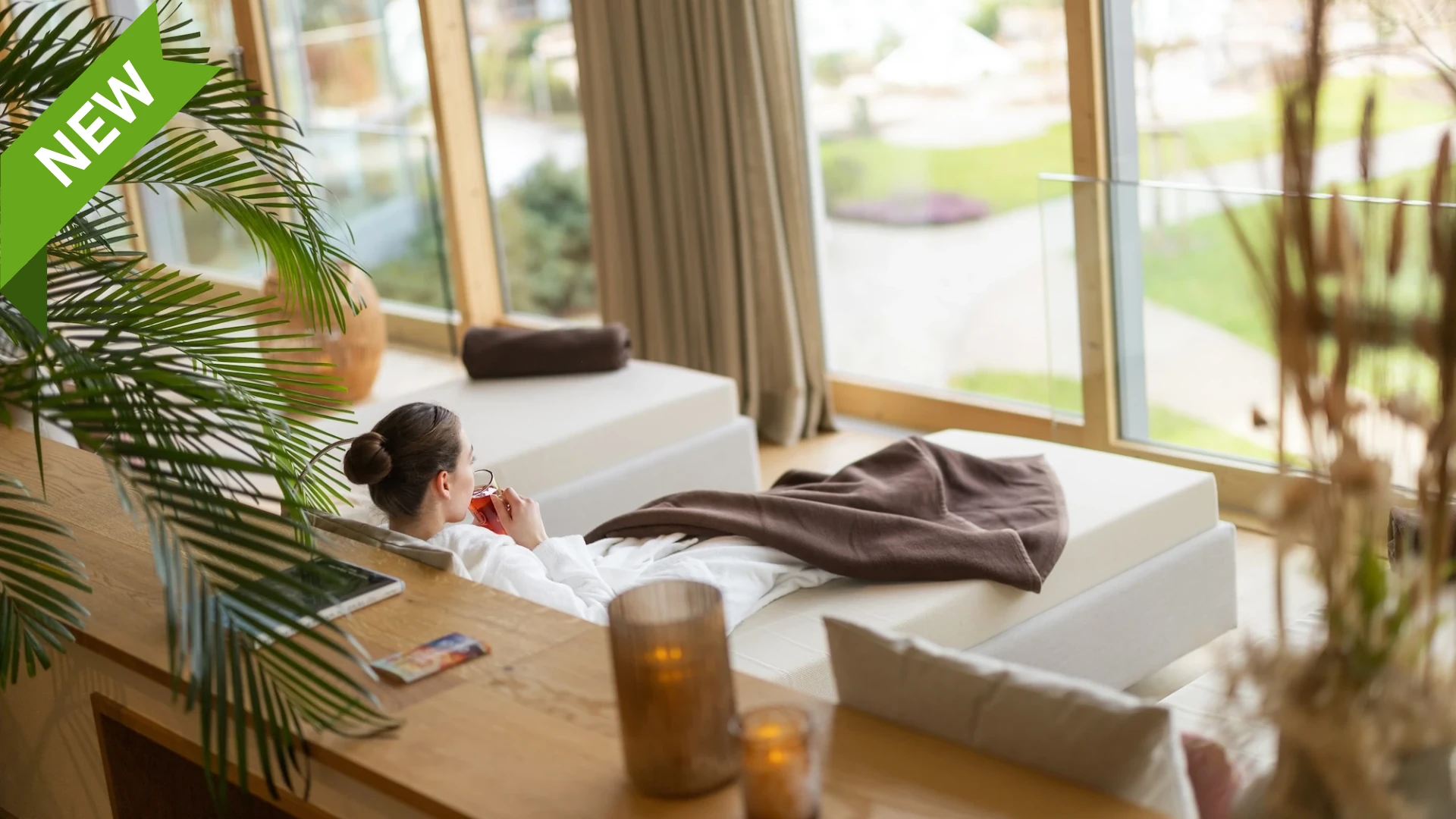 Frau relaxed mit einem Tee bei Wellness im Gutshof Spa des Hotel Deilmann mit Blick auf Poollandschaft