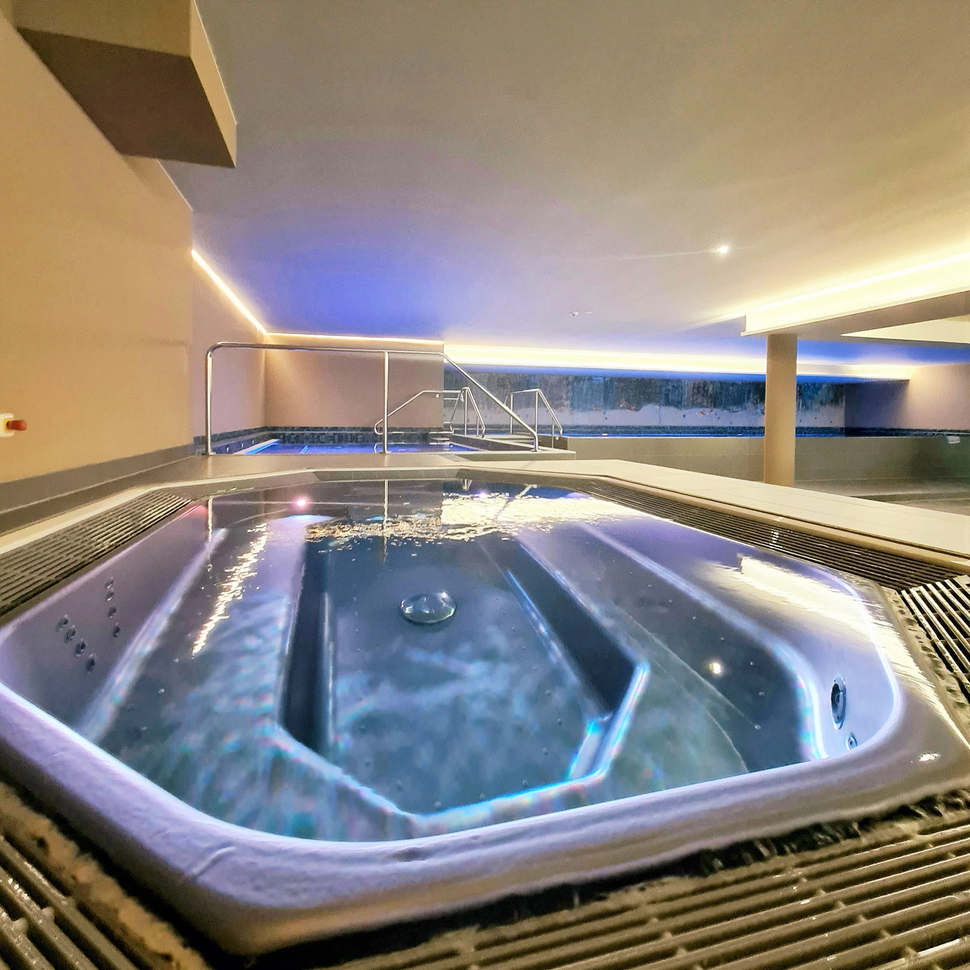 Beleuchteter, hochwertig eingerichteter Indoor Pool Bereich mit Whirlpool und weiteren Wasserbecken im Sante Royale Rügen.