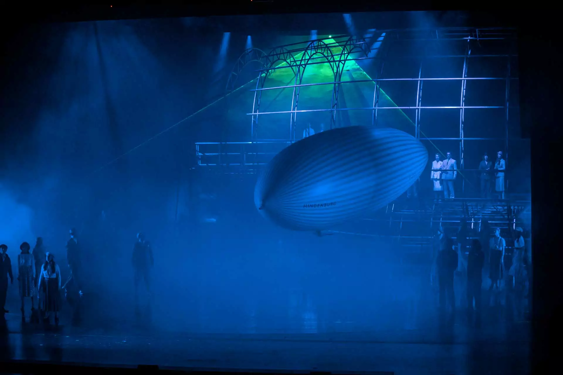 Bühnenbild mit Modell des Zeppelins Hindenburg und Schauspielern in historischer Kleidung bei Theateraufführung