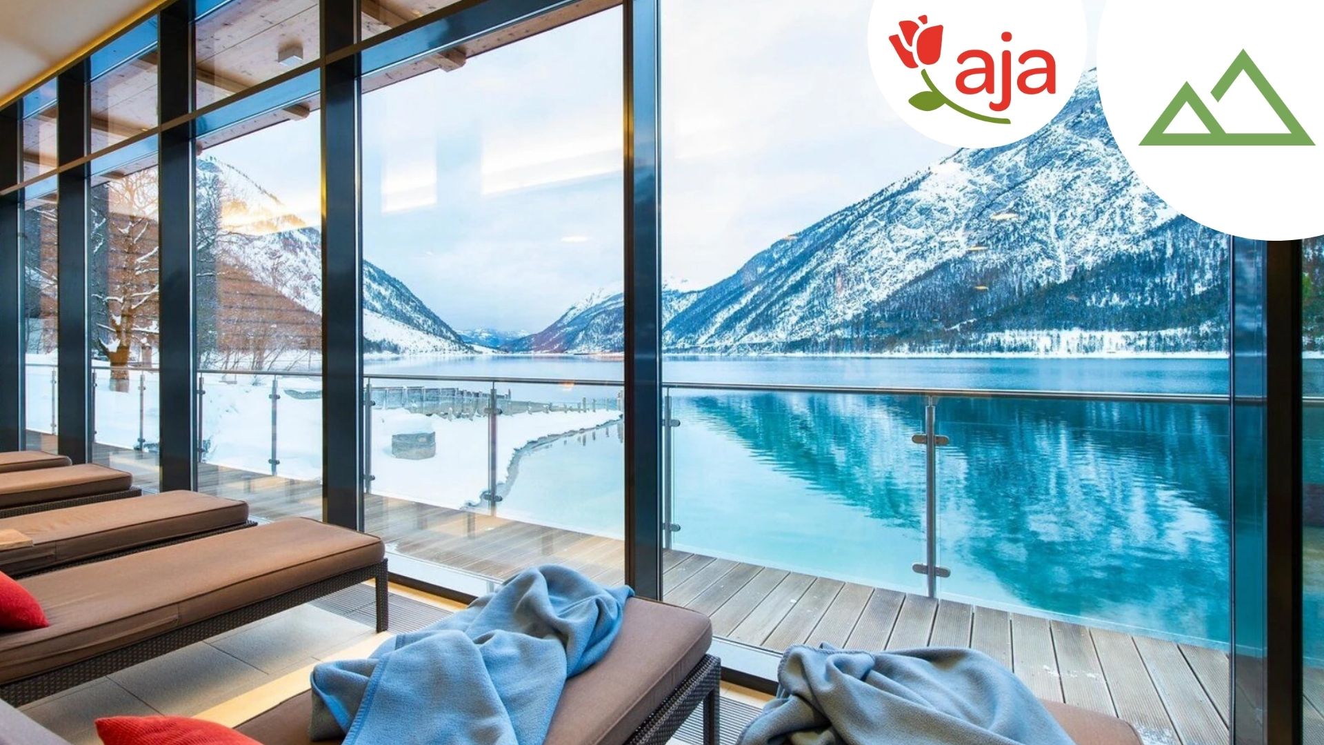 Blick aus dem Wellnessbereich im aja Fürstenhaus am Achensee auf den Achensee mit schneebedeckten Bergen im Hintergrund - mit Logo & Berge-Icon