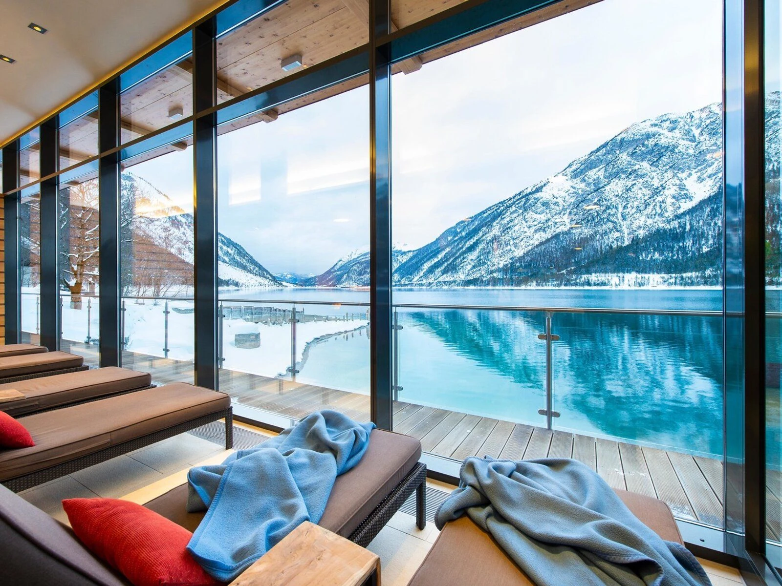 Blick aus dem Wellnessbereich im aja Fürstenhaus am Achensee auf den Achensee mit schneebedeckten Bergen im Hintergrund