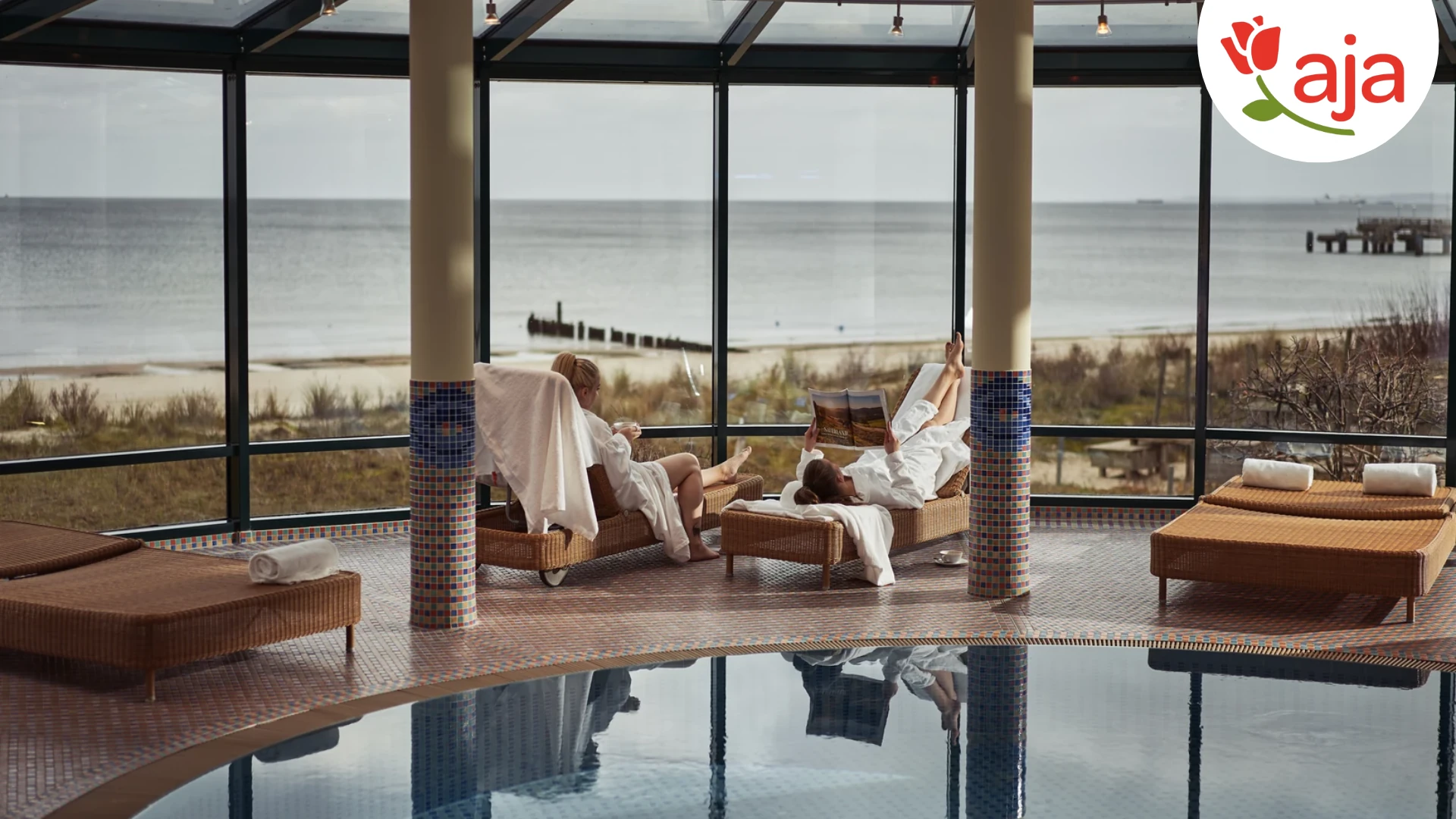 Entspannen mit Meerblick: Im aja Strandhotel Bansin genießen Gäste pure Erholung auf beaquemen Liegen im lichtdurchfluteten Wellnessbereich. Der direkte Blick auf die Ostsee und den feinsandigen Strand schafft eine einzigartige Atmosphäre der Ruhe und Gelassenheit. -mit Logo
