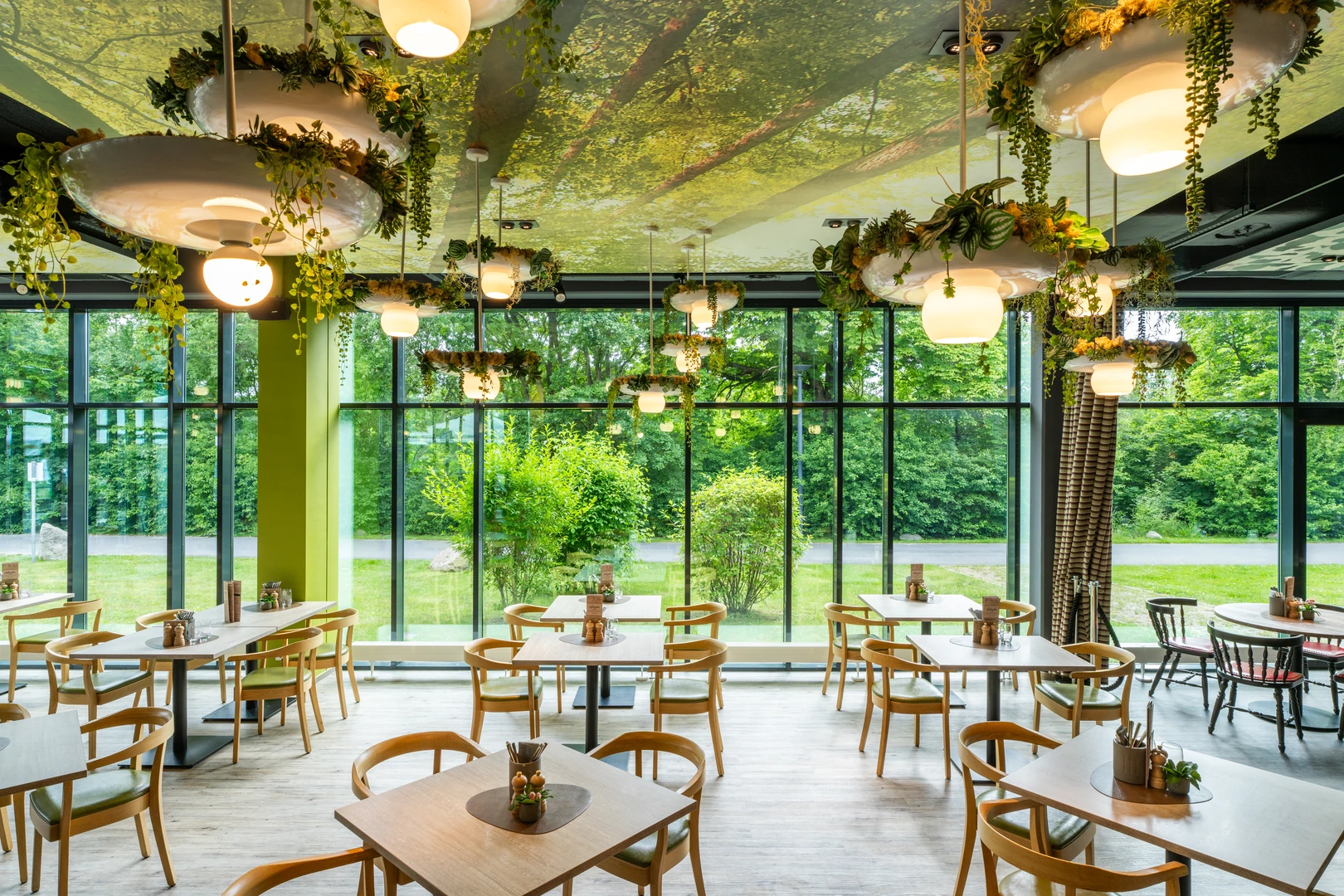 Das Restaurant im aja Resort Bad Saarow besticht durch seine moderne Einrichtung mit natürlichem Flair. Große Fensterfronten schaffen eine helle und freundliche Atmosphäre und bieten einen Ausblick ins Grüne. Die stilvolle Dekoration mit Pflanzen und natürlichen Elementen sorgt für ein entspanntes Ambiente, das perfekt zum Genießen von Mahlzeiten geeignet ist.