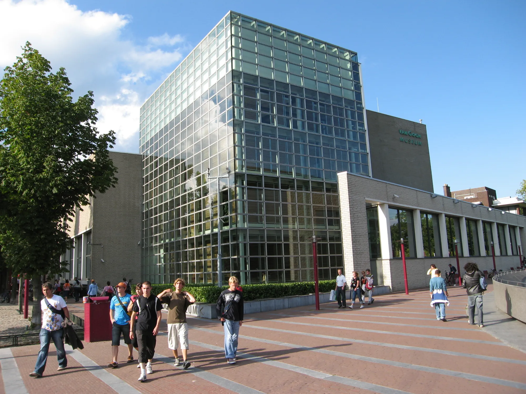 Außenansicht des Van Gogh Museums an einem sonnigen Tag, umgeben von Besuchern, die die beeindruckende Architektur des Gebäudes bewundern.