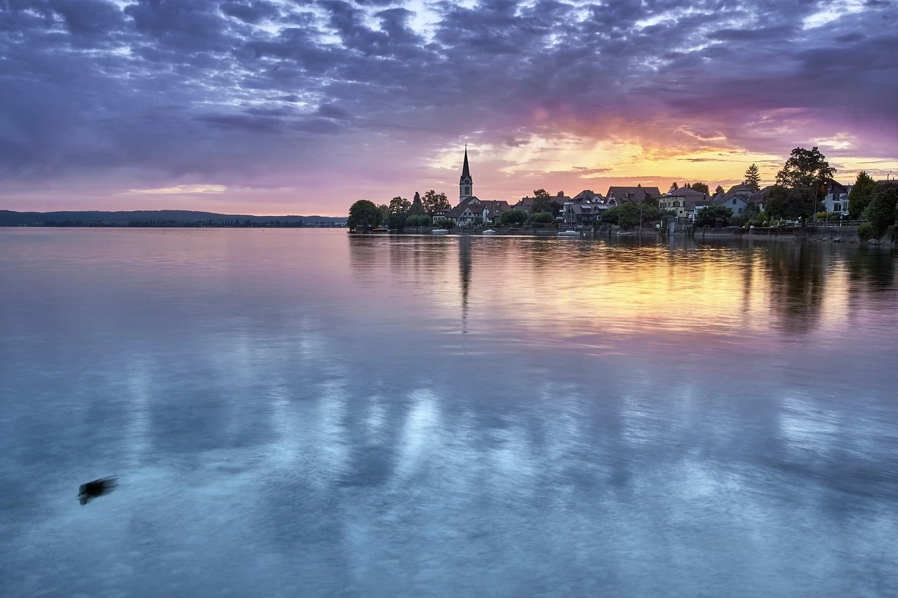 Ortschaft mit Kirche am Bodensee in der Dämmerung.