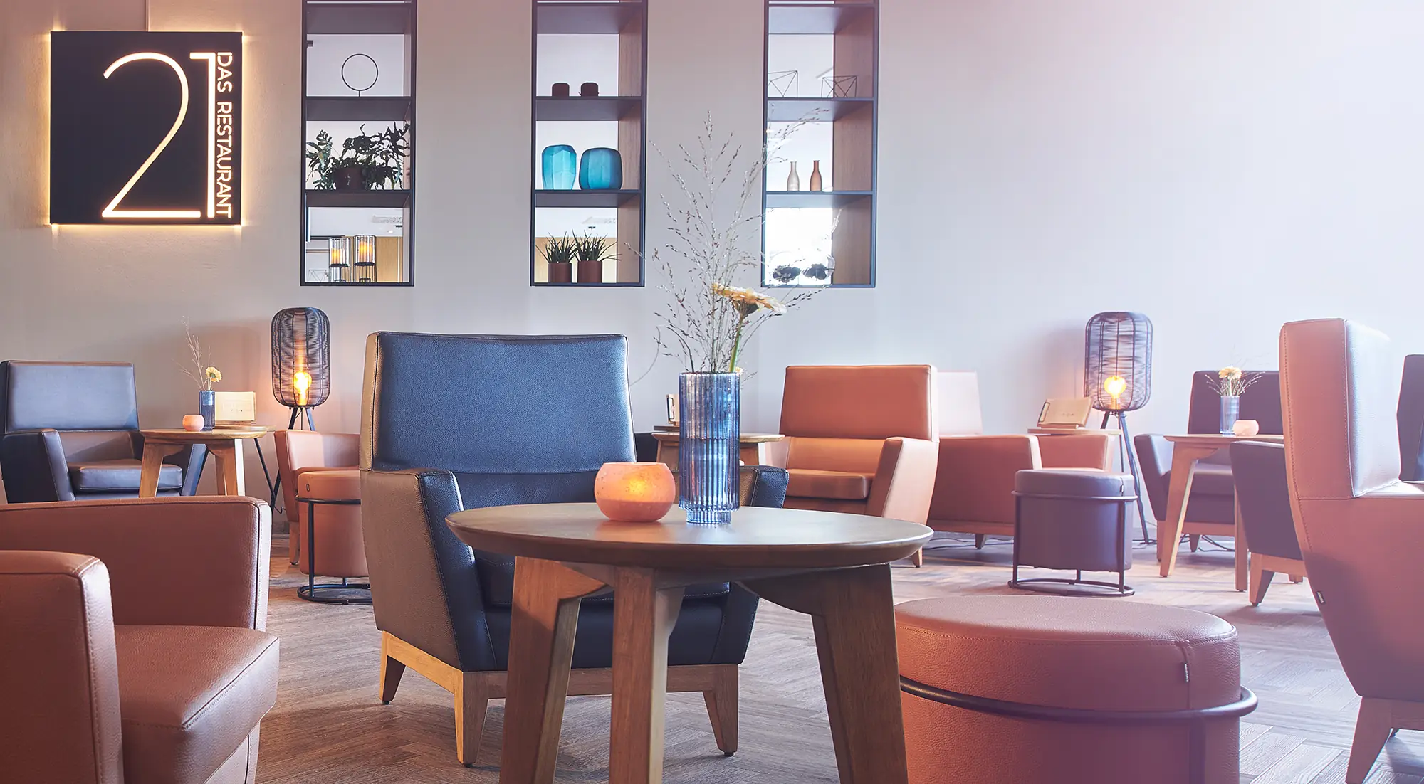 Gemütliches Bistro im Atlanta Hotel International Stadt Leipzig. Es stehen Sessel und kleine Tische mit Kerzen im Bistro.