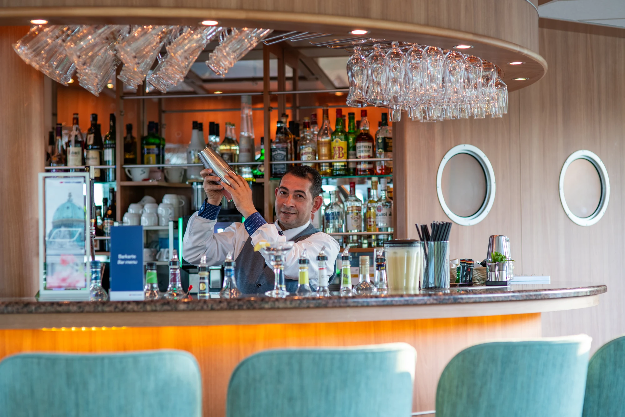 Mann beim Cocktails mixen hinter der Bar mit Flaschen und Gläsern im Salon der RHEIN MELODIE