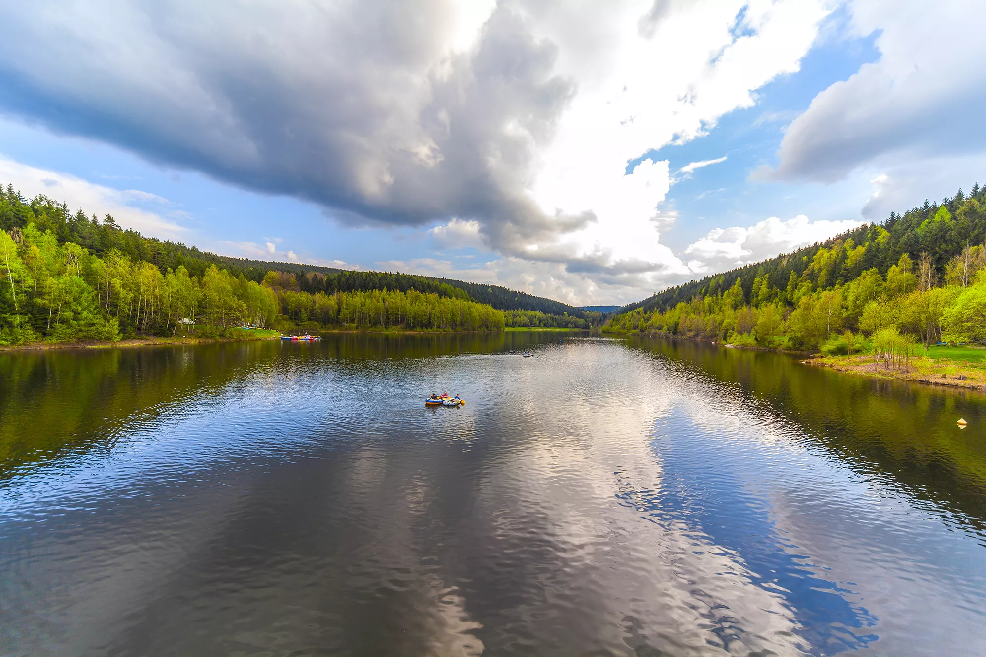 Blick auf einen See in der Nähe von Bad Brambach mit Ruderboot und umgeben von grünen Bäumen