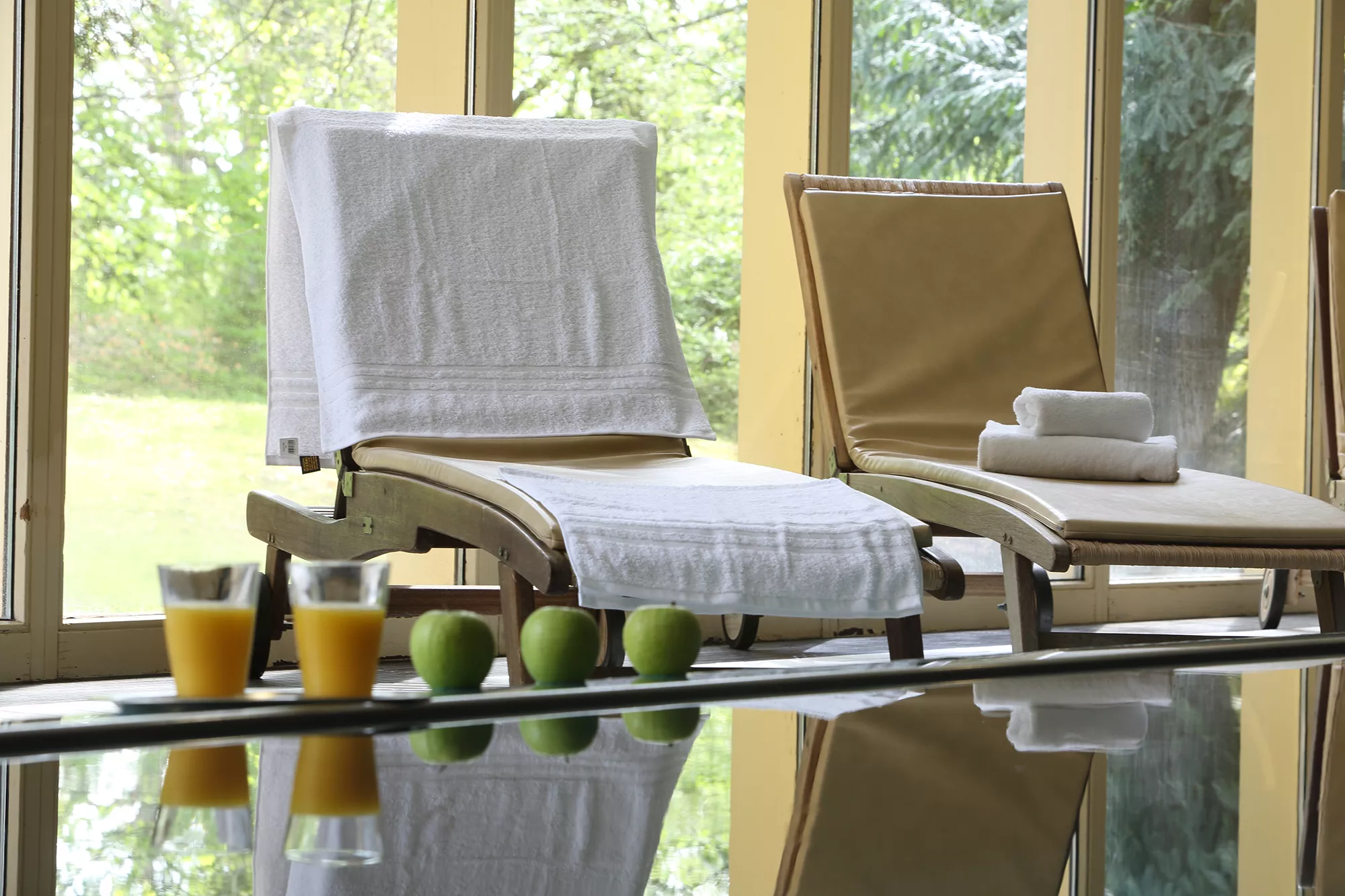 Blick auf bequeme Poolliegen sowie Obst und Gläser mit Orangensaft aufgestellt am Poolrand im Hotel Dolce Bad Nauheim