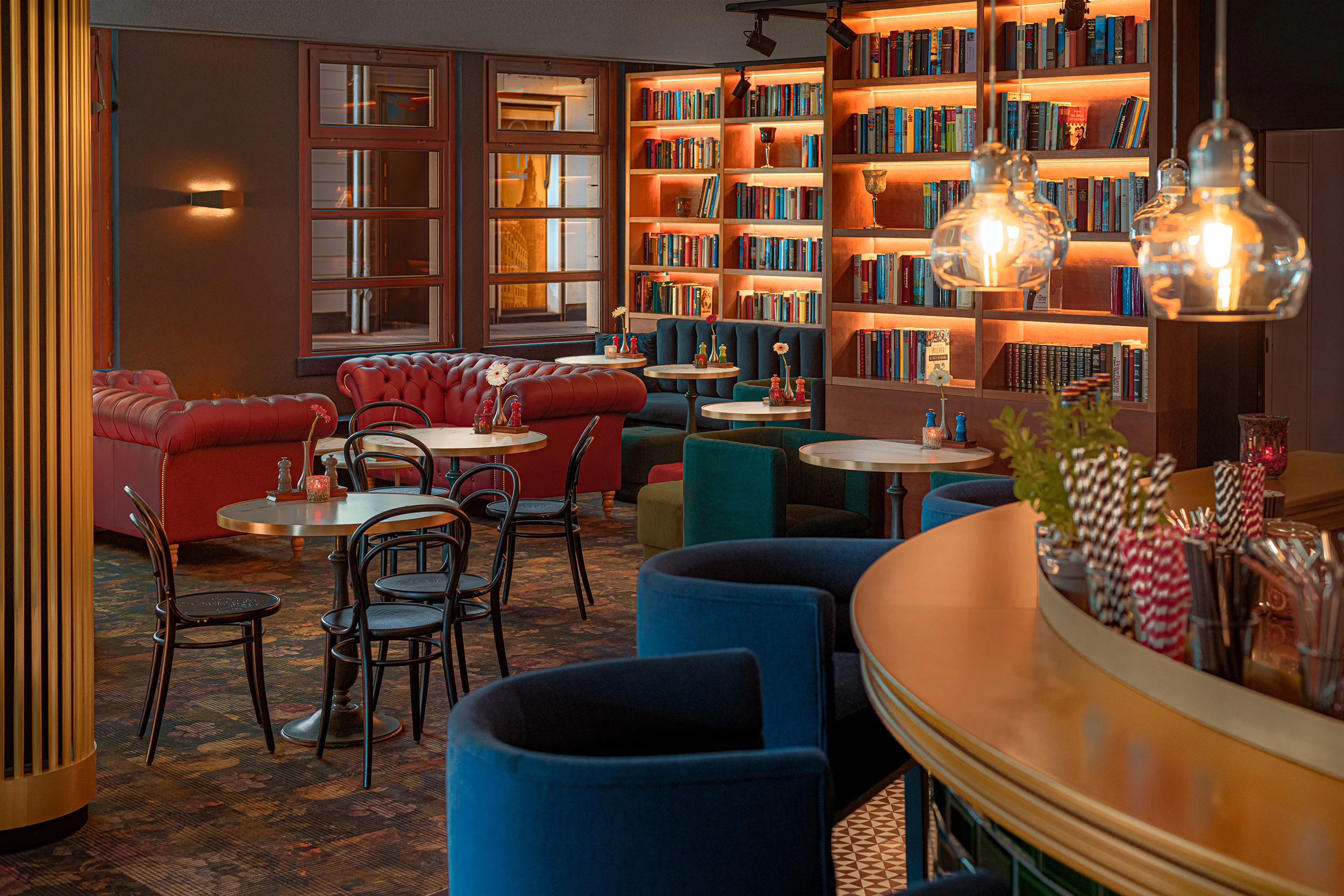 Abendlicher Blick in das Bistro und Bar im Hilton Dresden - im Hintergrund sind Bücherregale