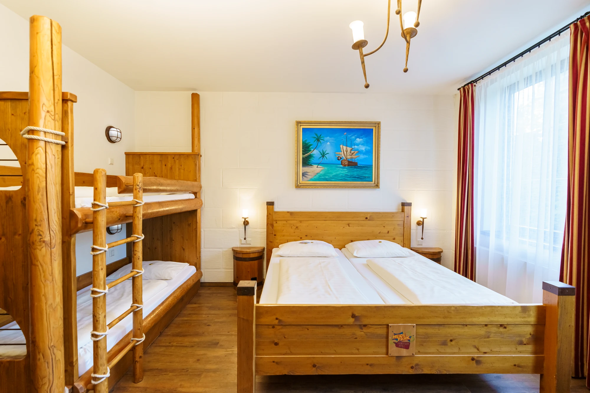 Beispiel Piratenzimmer mit Doppelbett und Etagenbett mit einem Bild mit Schiff an der Wand im Abenteuerhotel