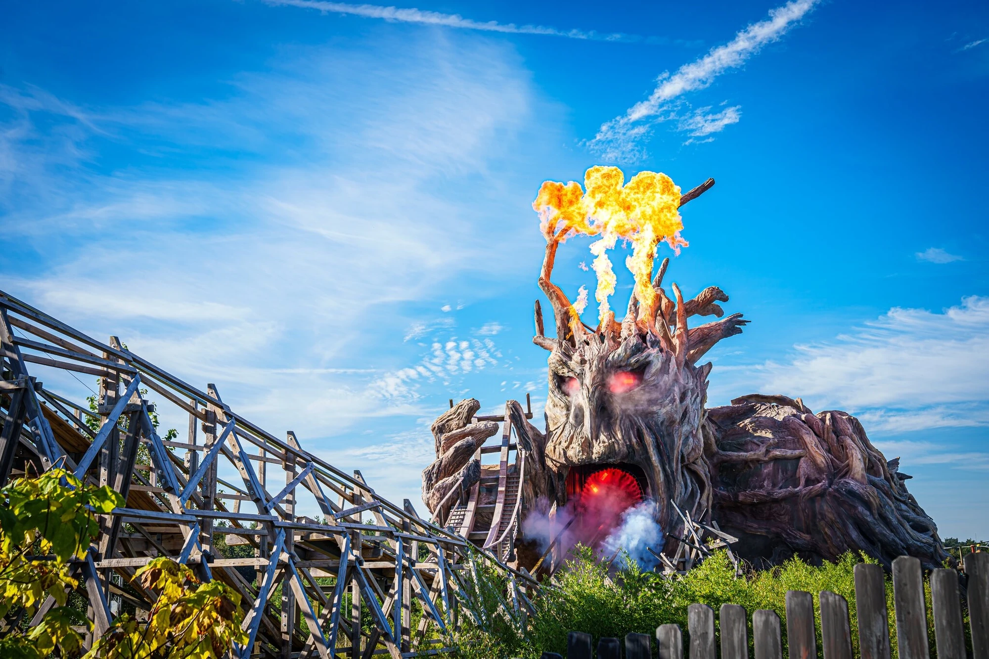 Achterbahn Colossos mit einem animierten Monster aus Holz im Hintergrund mit Feuer aus dem Kopf im Heide Park