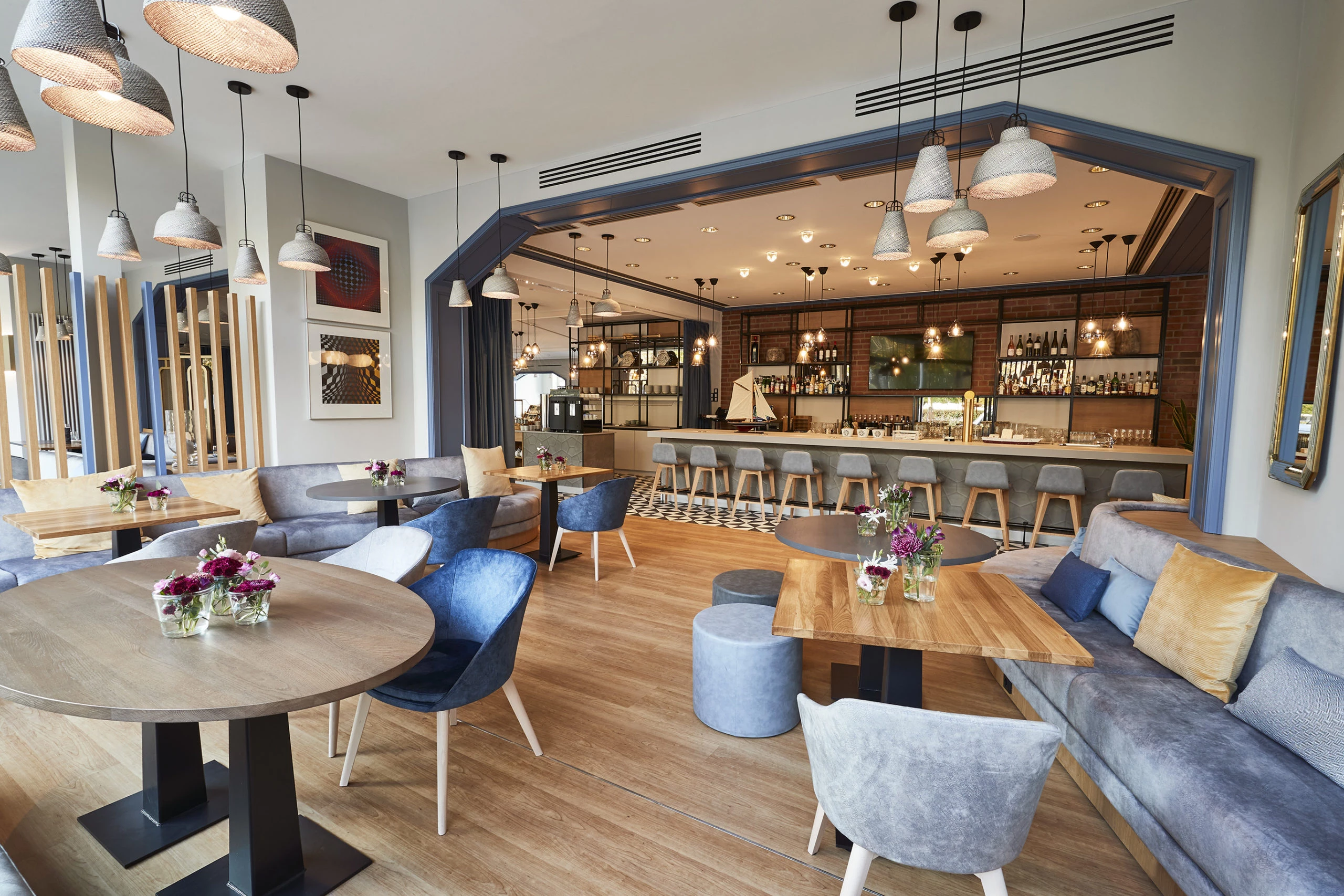 Die stilvolle Lounge im Steigenberger Hotel Conti Hansa Kiel bietet ein modernes und einladendes Ambiente. Helle Farben, gemütliche Sitzmöglichkeiten und dezente Beleuchtung schaffen eine entspannte Atmosphäre. Die offenen Räumlichkeiten mit Holz- und Polstermöbeln sind ideal für informelle Treffen oder entspannte Stunden. Im Hintergrund befindet sich eine schicke Bar, die den Raum perfekt abrundet und für eine angenehme Atmosphäre sorgt. Frische Blumen auf den Tischen verleihen dem Raum einen zusätzlichen Hauch von Eleganz.