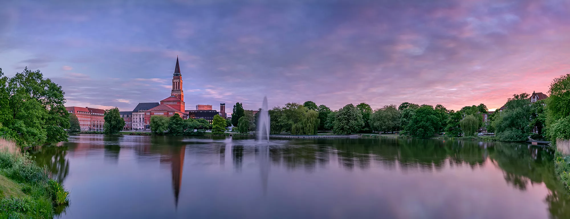 Panorama vom kleinen Kiel mit Rathausturm und Springbrunnen in der Abenddämmerung mit lila Himmel