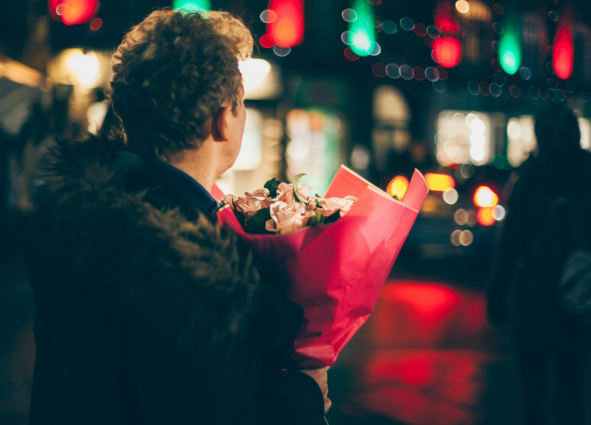 Partner hält in der Dunkelheit Blumen als Geschenk in der Hand