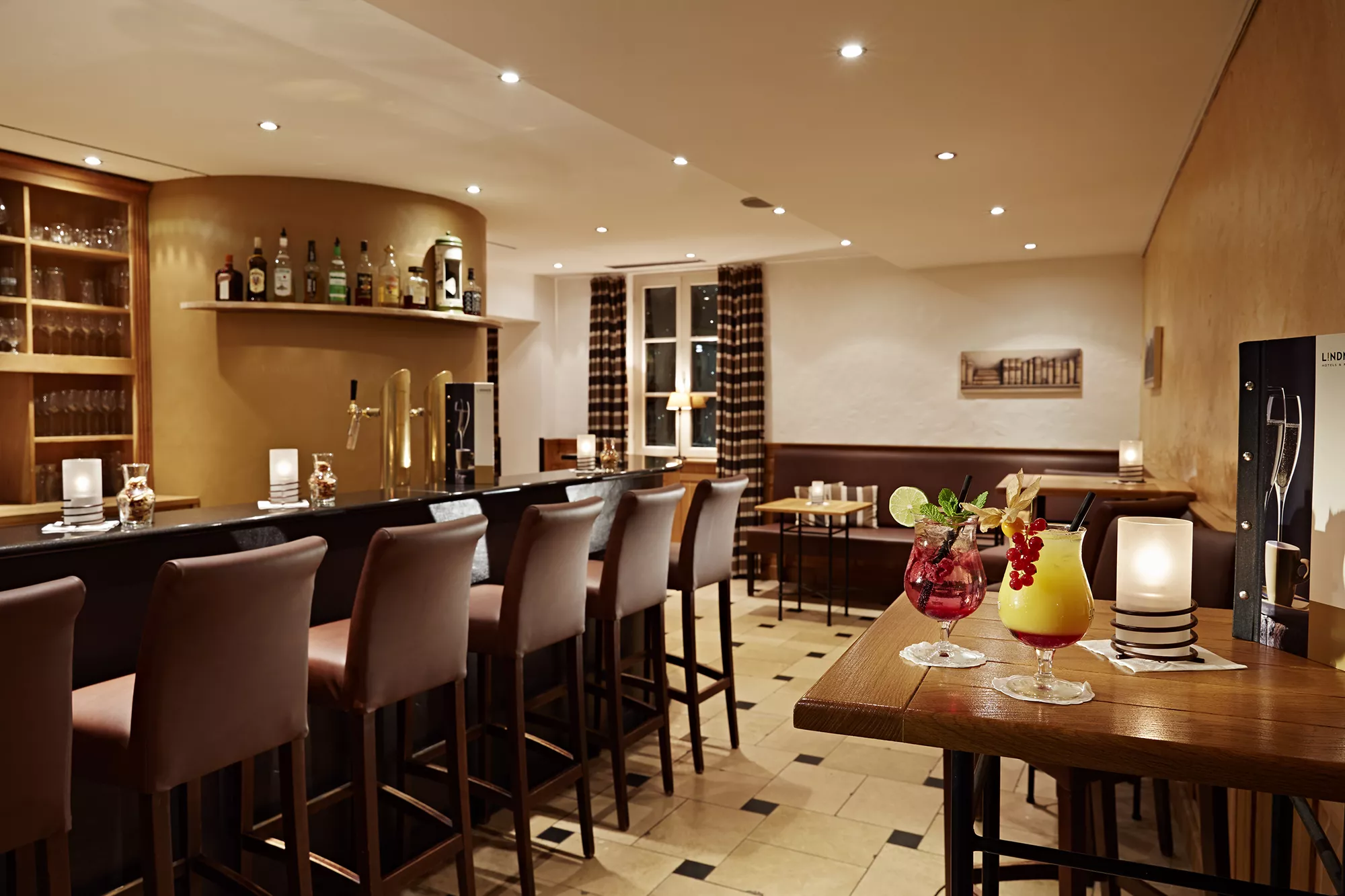 Abbildung der Bar im Lindner Hotel & Resort in Binshof, Speyer mit langer Theke und gemütlichen Barhockern in warmen Brauntönen gehalten