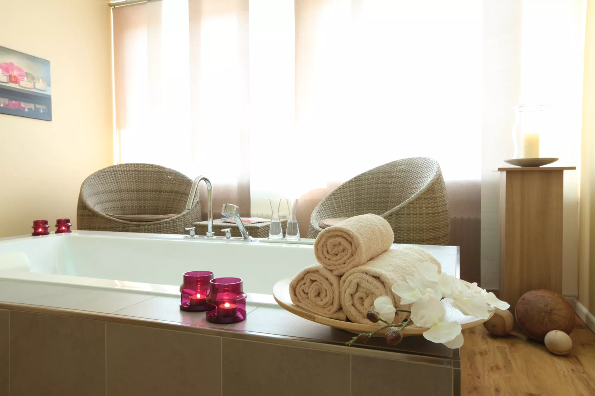 Blick in einen Behandlungsraum des Beautybereich im Lindner Hotel Wiesensee mit Badewanne, Korbmöbeln und am Wannenrand stehenden Kerzen