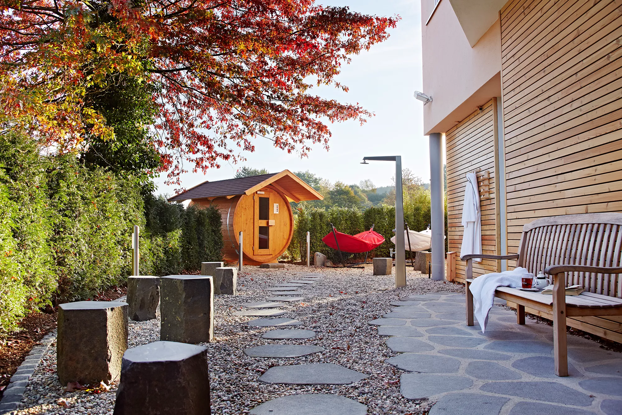 Saunabereich mit Blick auf eine Fasssauna, Hängematten und Außendusche in naturnaher Umgebung im Lindner Hotel & Sporting Club Wiesensee