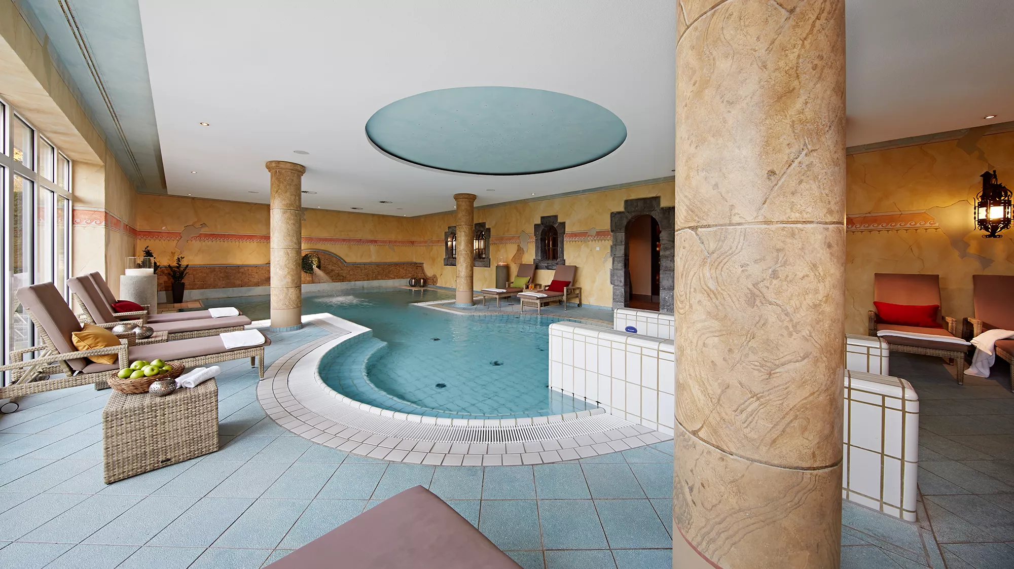 Blick in den hellen Poolbereich des Lindner Hotel & Sporting Club Wiesensee mit Ruheliegen und großen Bodenfenstern