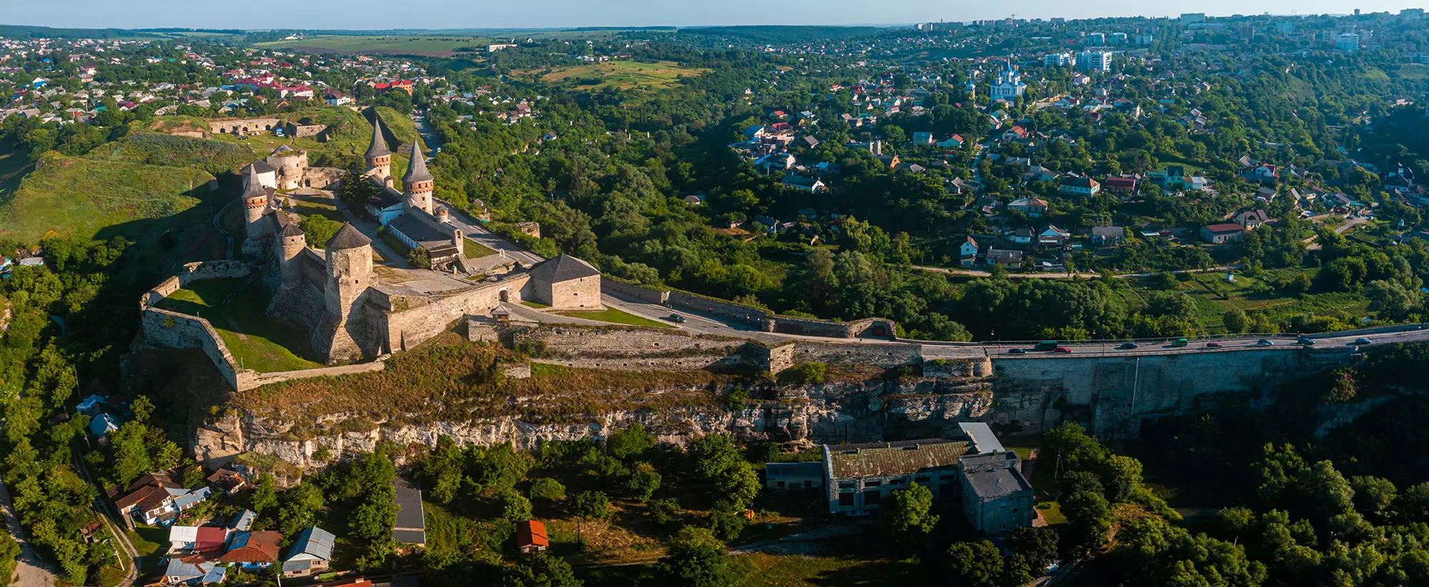 Vogelperspektive auf die Festung Useldange im Guttland, umgeben von reichhaltiger, unberührter Natur. Die grünen Landschaften und die historische Architektur harmonieren in einem beeindruckenden Panorama.