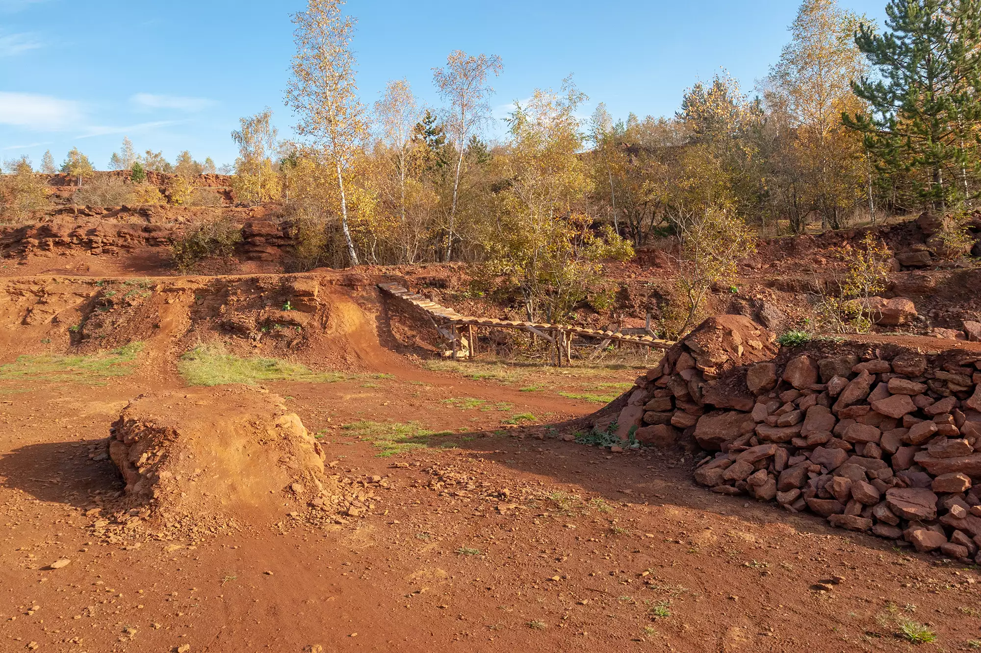 Die Minett-Landschaft in Luxemburg, geprägt von eisenerzhaltigem roten Boden. Die markanten Erhebungen und die charakteristische Farbgebung schaffen eine einzigartige und beeindruckende Naturkulisse.