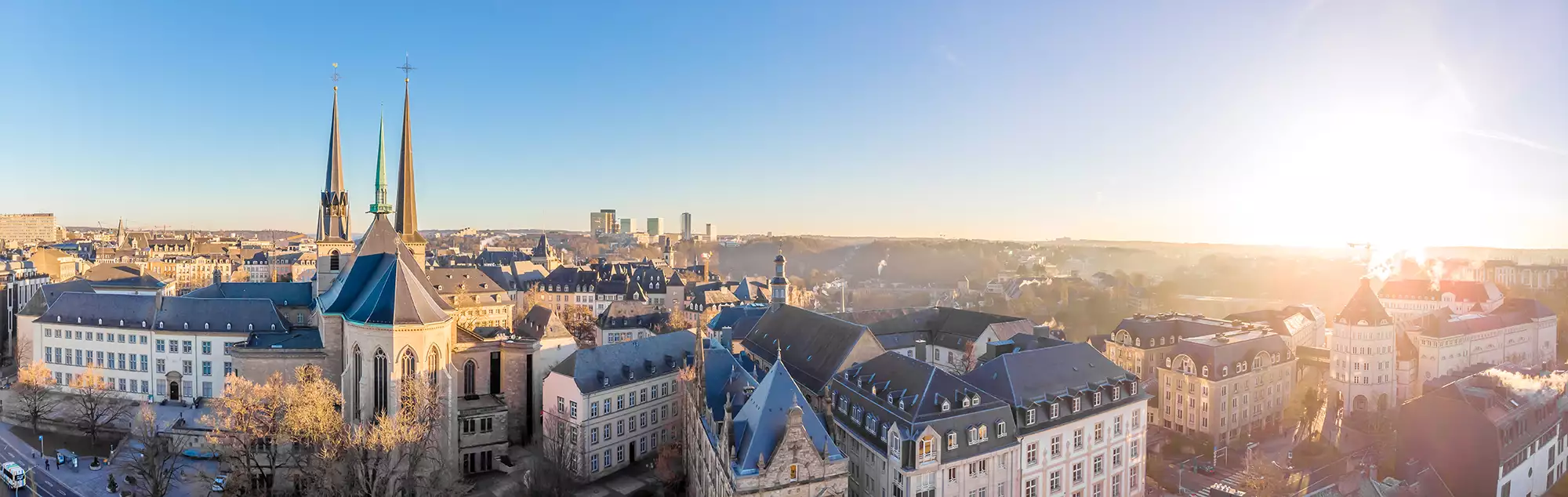 Panoramabild im sonnigen Winter mit Blick über die Dächer von Luxemburg Stadt. Die strahlende Sonne beleuchtet die dezent verschneiten Dächer und verleiht der Szene eine klare, fröhliche Atmosphäre.