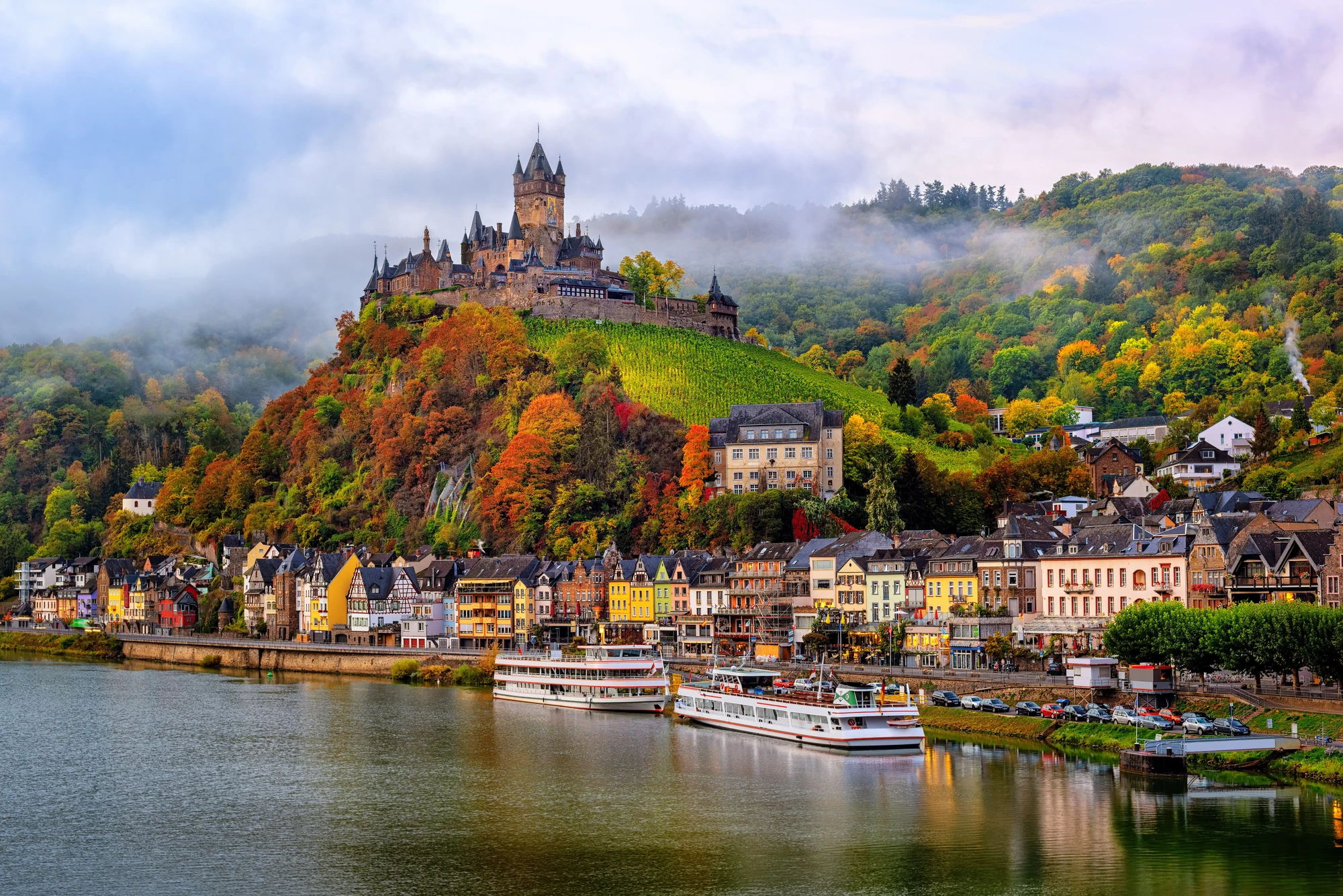 Burg Cochem an der Mosel im Herbst mit bunten Blättern und der Stadt Cochem