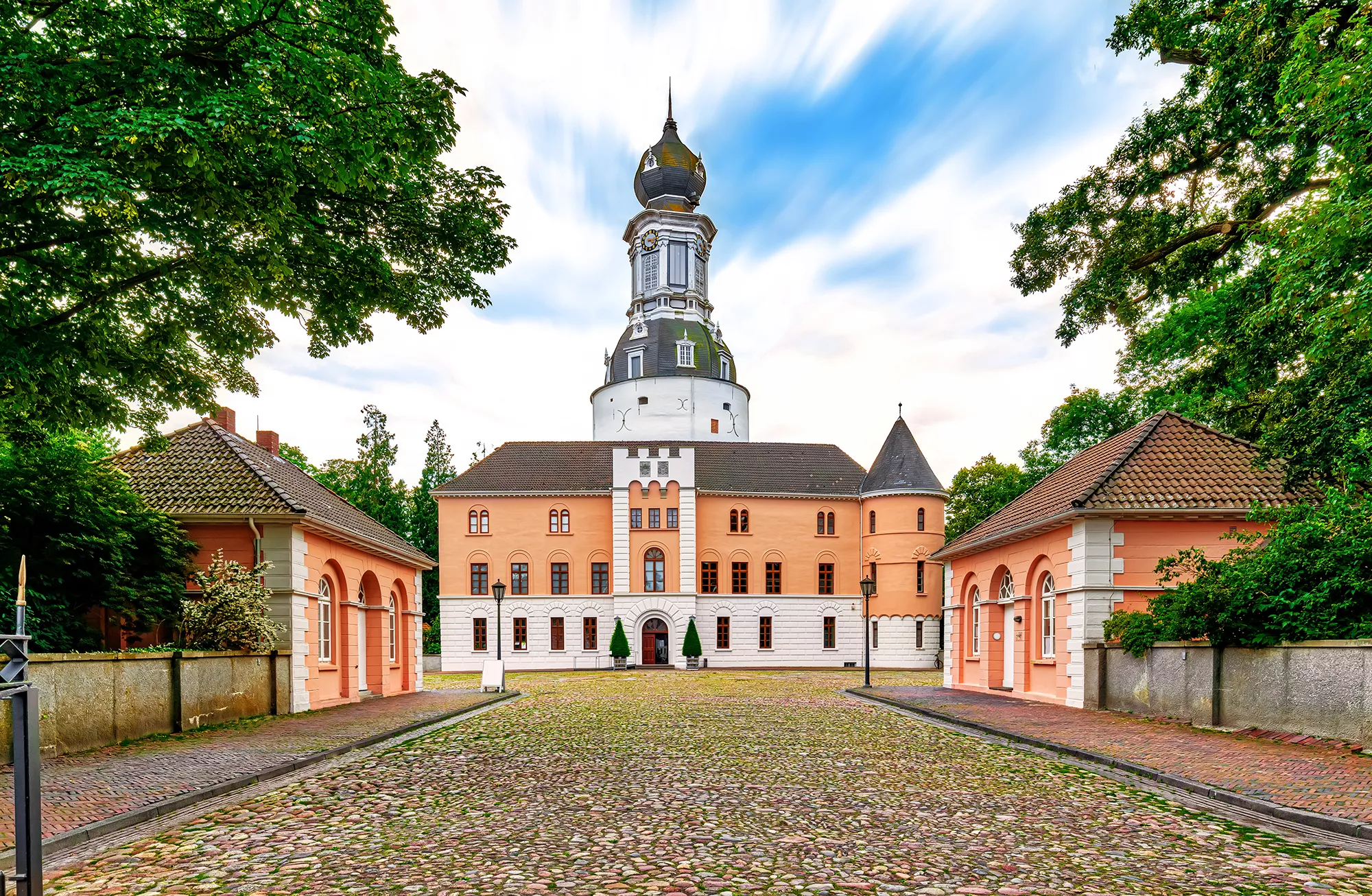 Blick über den Schlossplatz auf den Eingang des Schloss Jever inmitten des Schlossparks