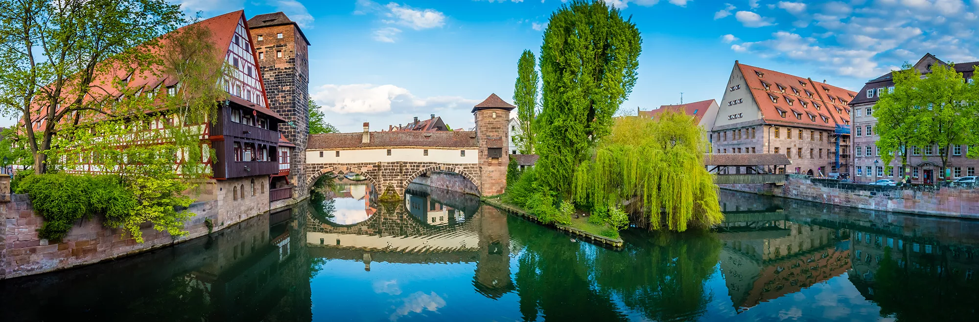 Panoramabild von Wasserturm, Henkerbrücke, Henkerhaus und Henkersteg in Nürnberg mit Spiegelung in der Pegnitz