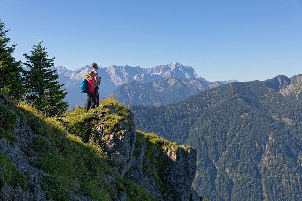 Wanderer steht auf Klippe und blickt in die Ferne.