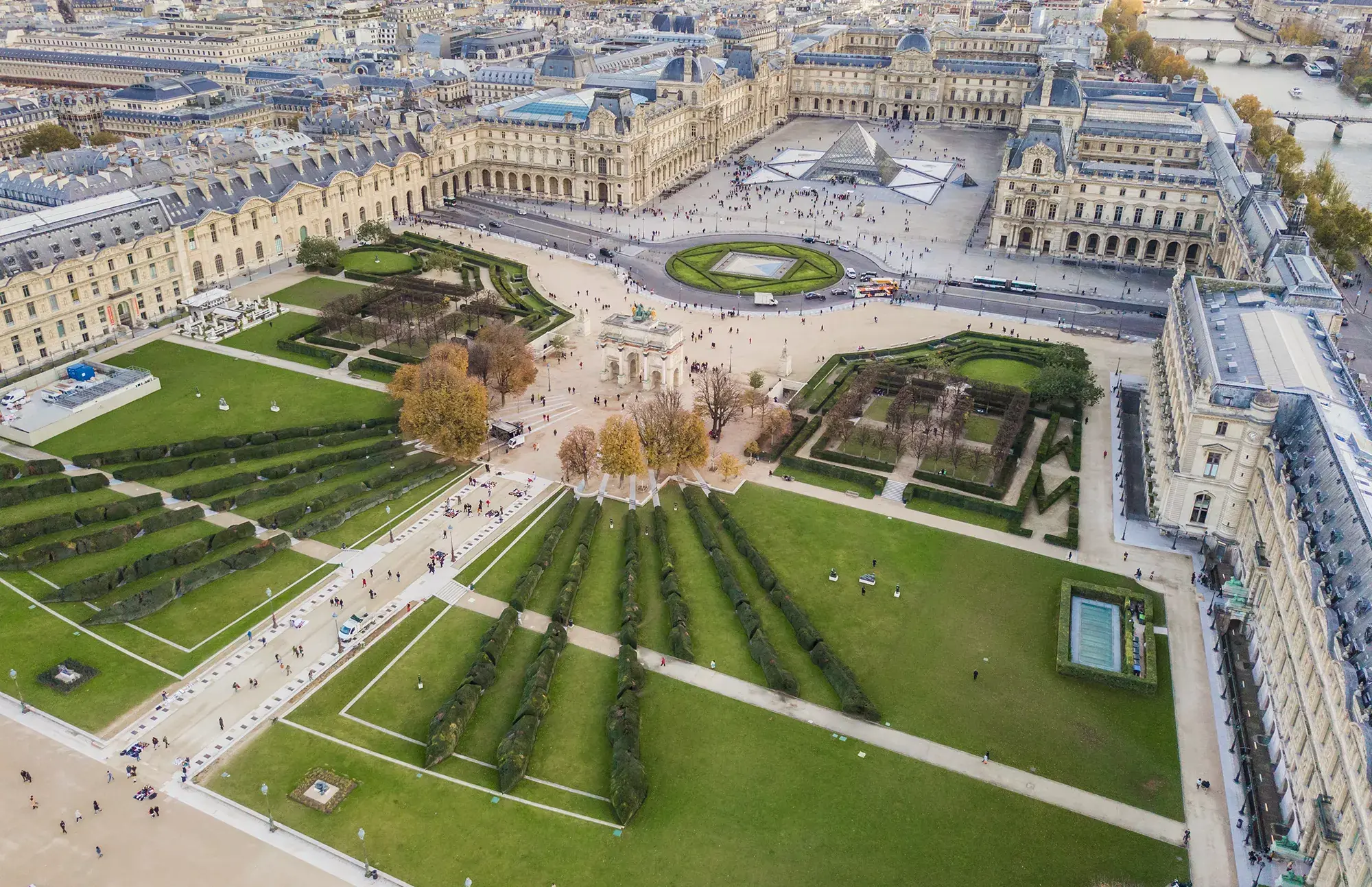 Luftaufnahme des Louvre bei Tageslicht, mit dem Innenhof und seinen schön gestalteten Gartenanlagen.