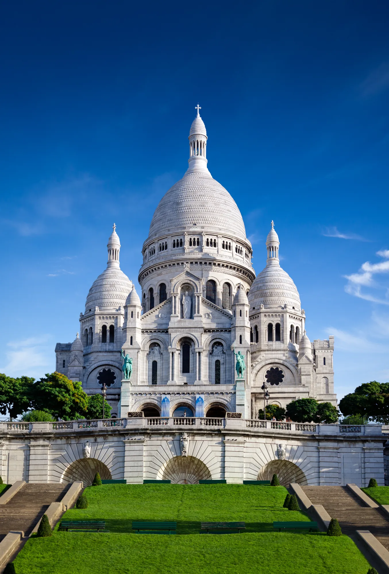Beeindruckendes weißes Sacré-Cœur-Basilika-Gebäude in Montmartre, umgeben von einer gepflegten grünen Parkanlage.