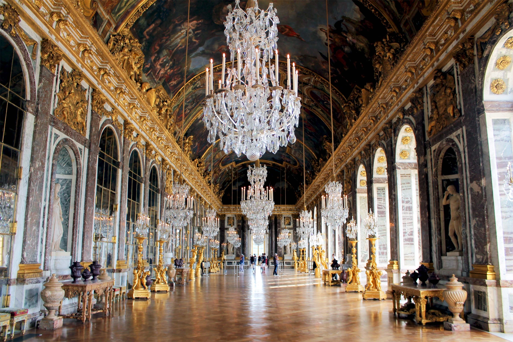 Spiegelsaal im Schloss Versailles, mit prunkvollen Spiegeln und opulenter Dekoration, die das Licht reflektiert und eine beeindruckende Atmosphäre schafft.