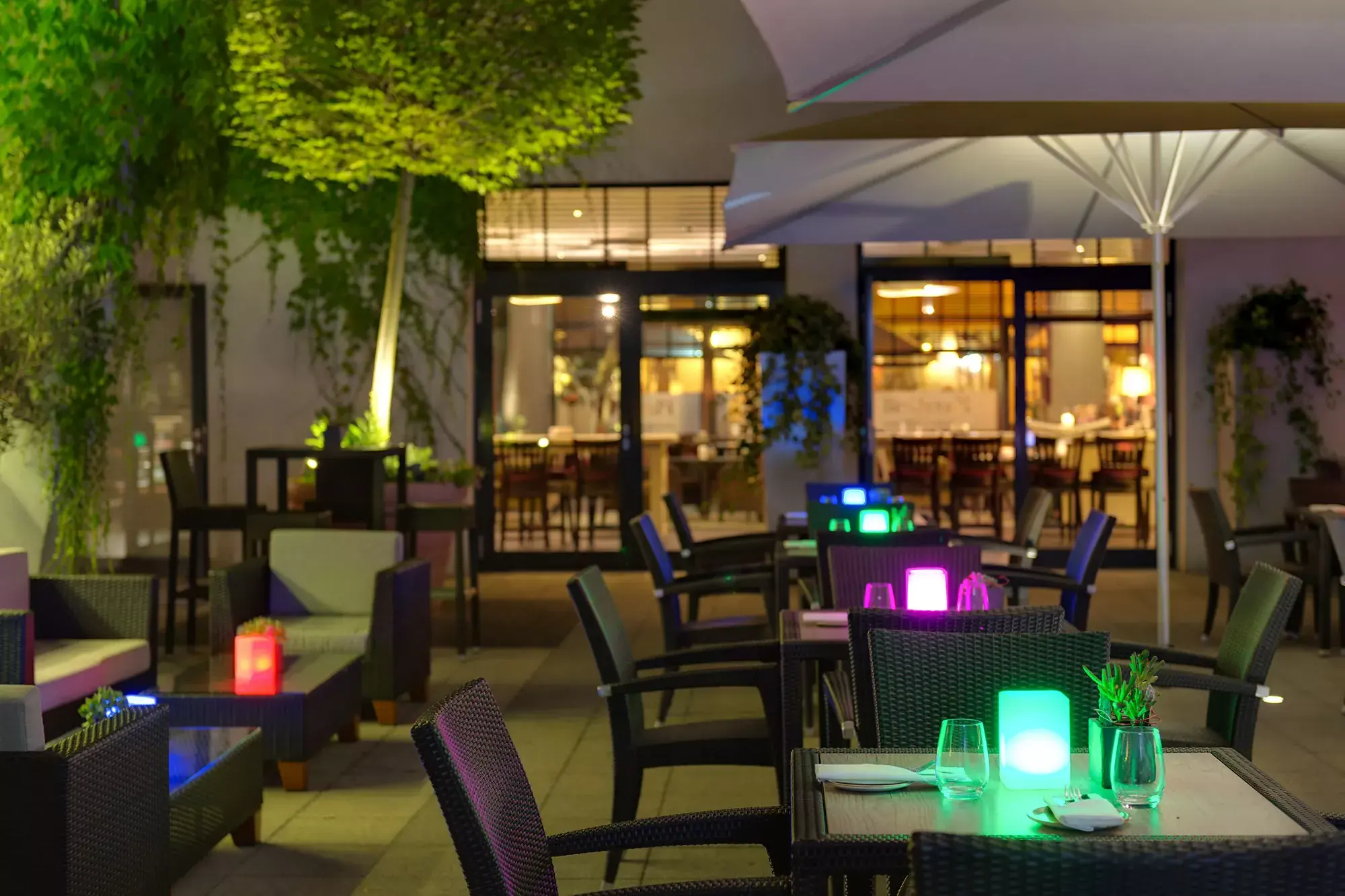 Außenterrasse im Park Plaza Hotel Trier am Abend mit Tischen und Stühlen sowie Sitz-Lounges