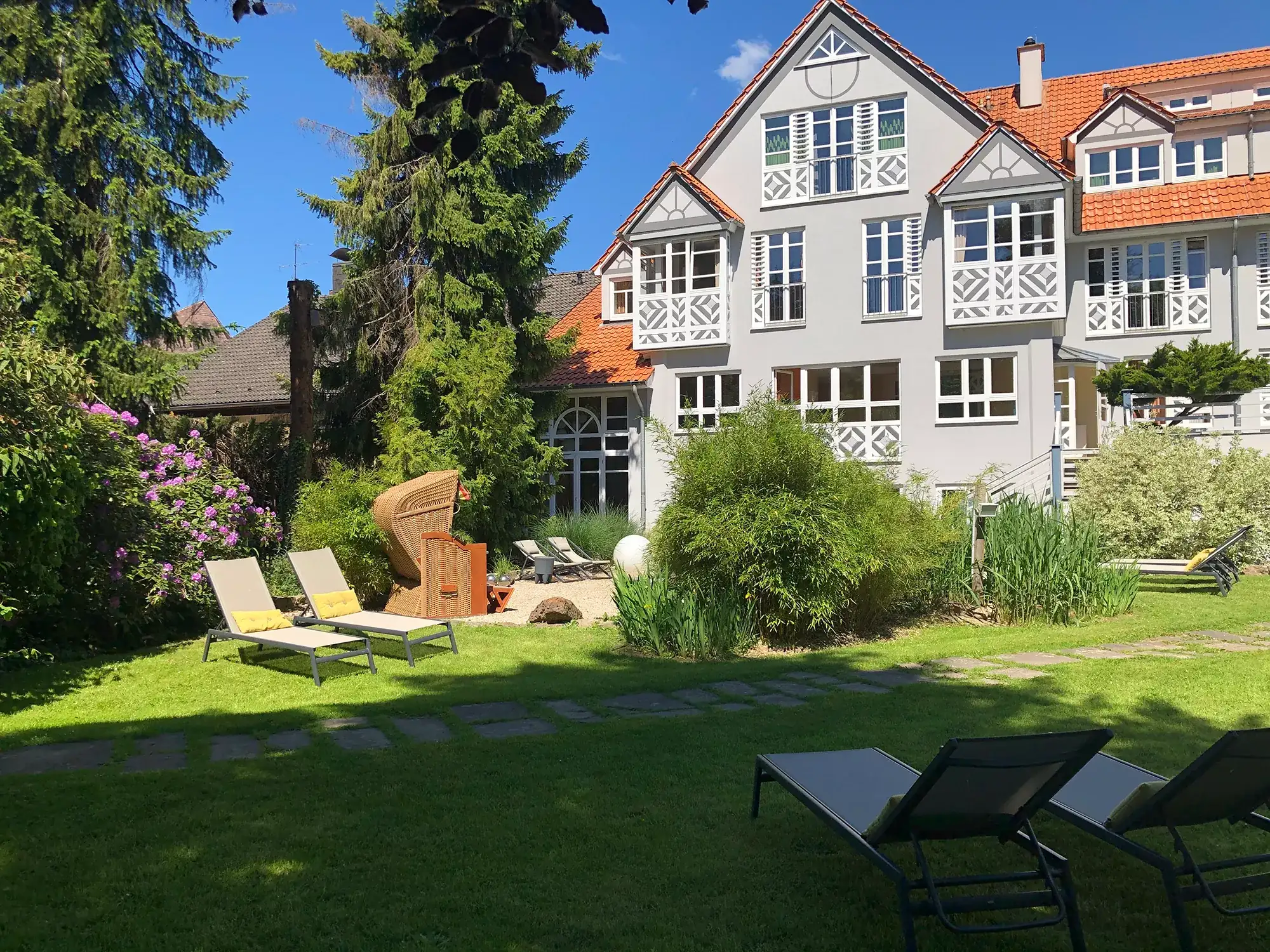 Garten mit Liegen und Strandkorb und Blick auf die Außenansicht vom Romantisches Hotel Menzhausen